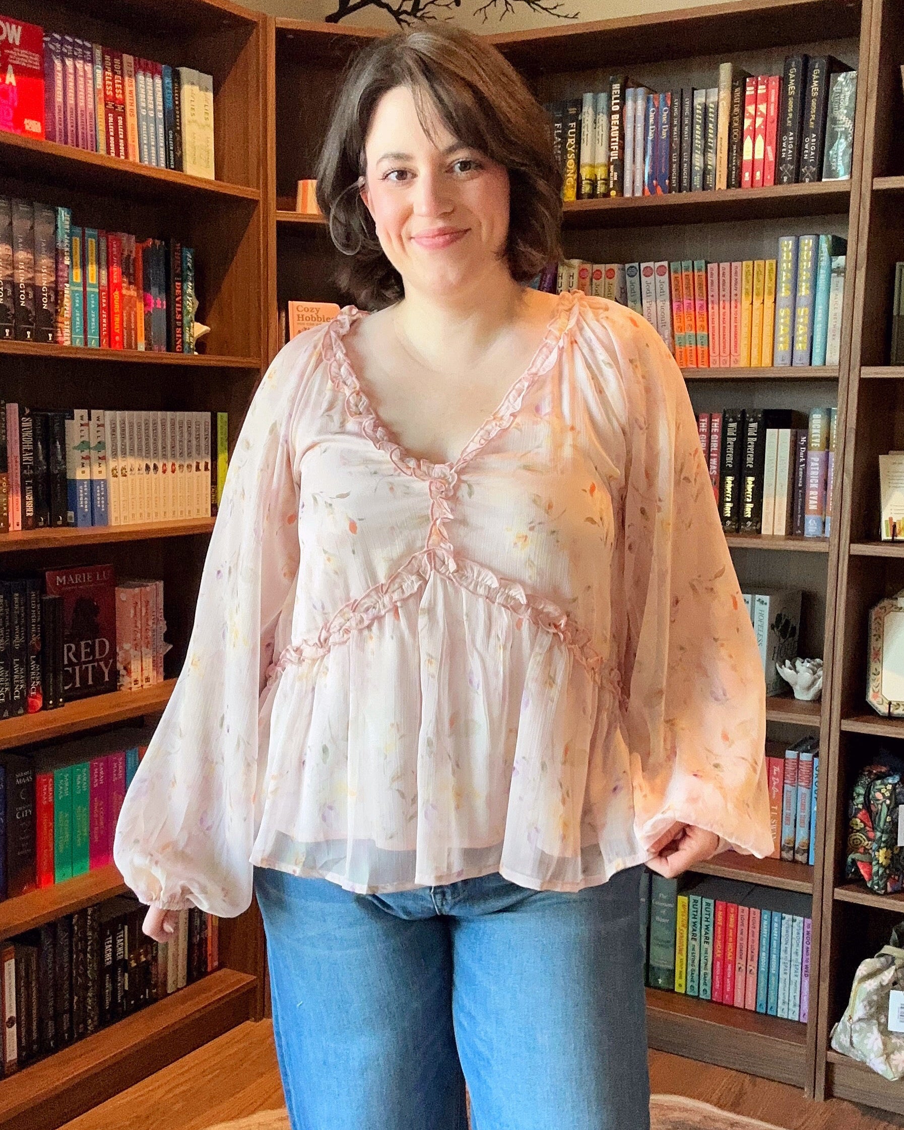 Woman standing in front of a bookshelf filled with books