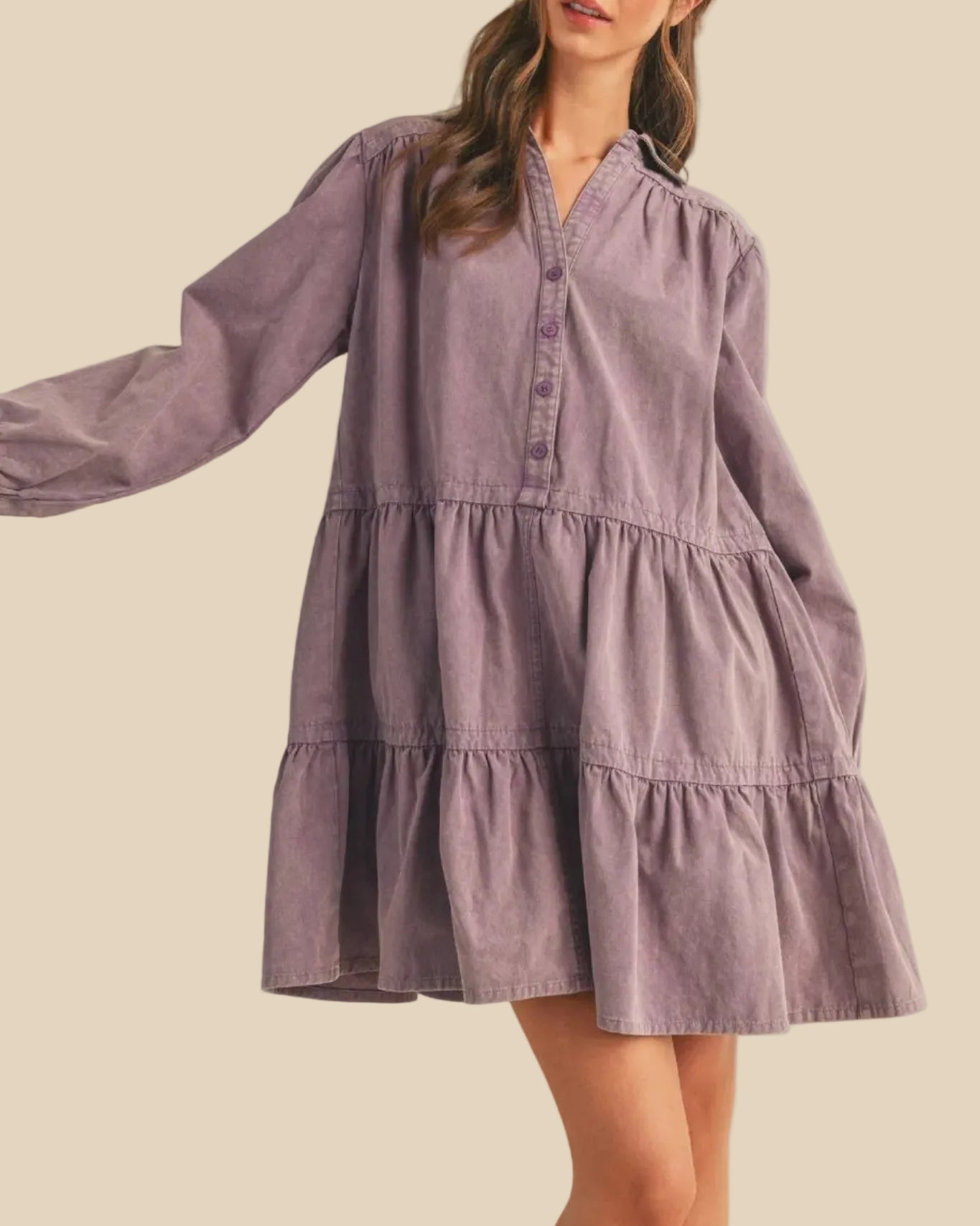 Woman wearing a purple tiered dress against a plain background