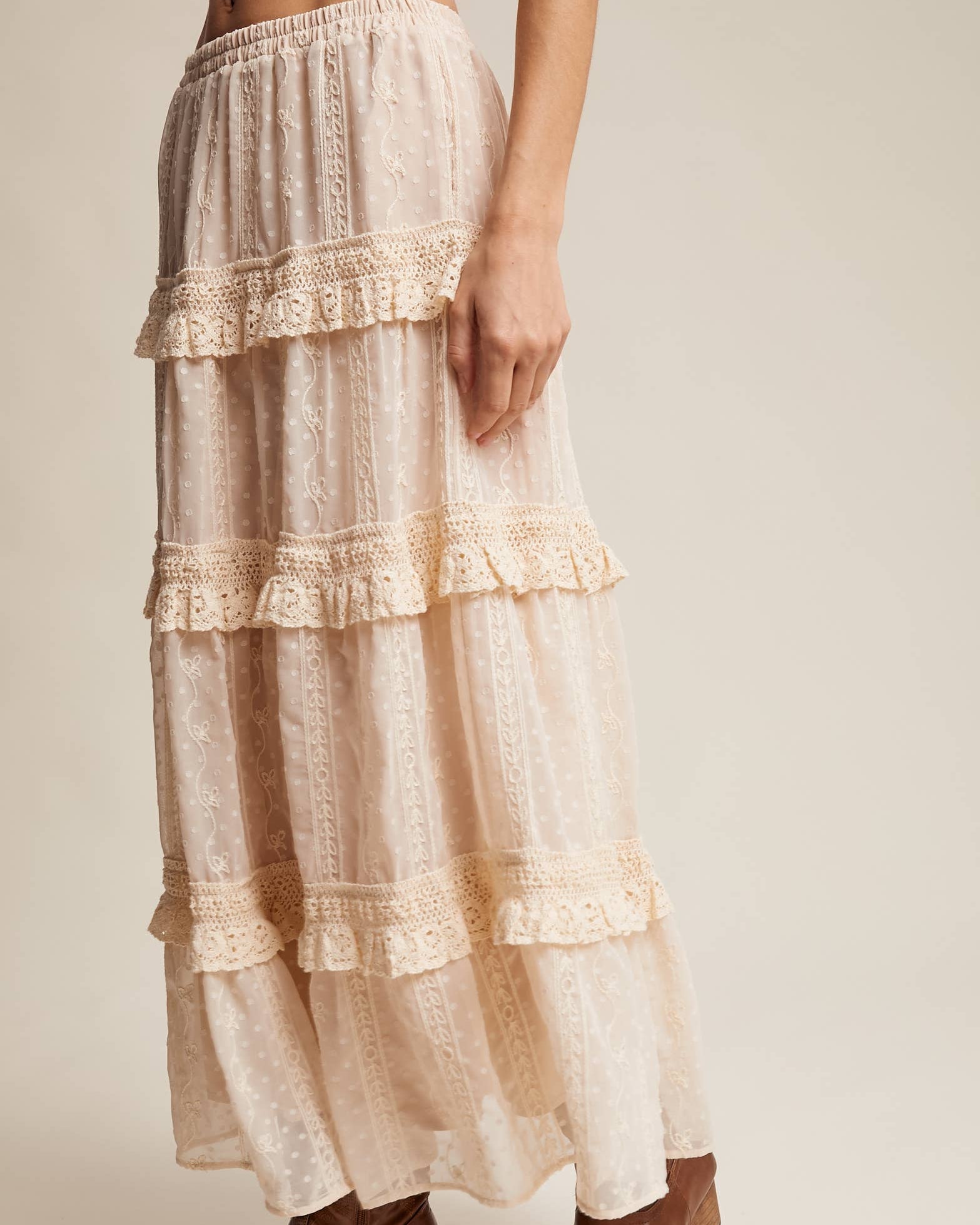 Long, tiered lace skirt worn by a person on a plain background