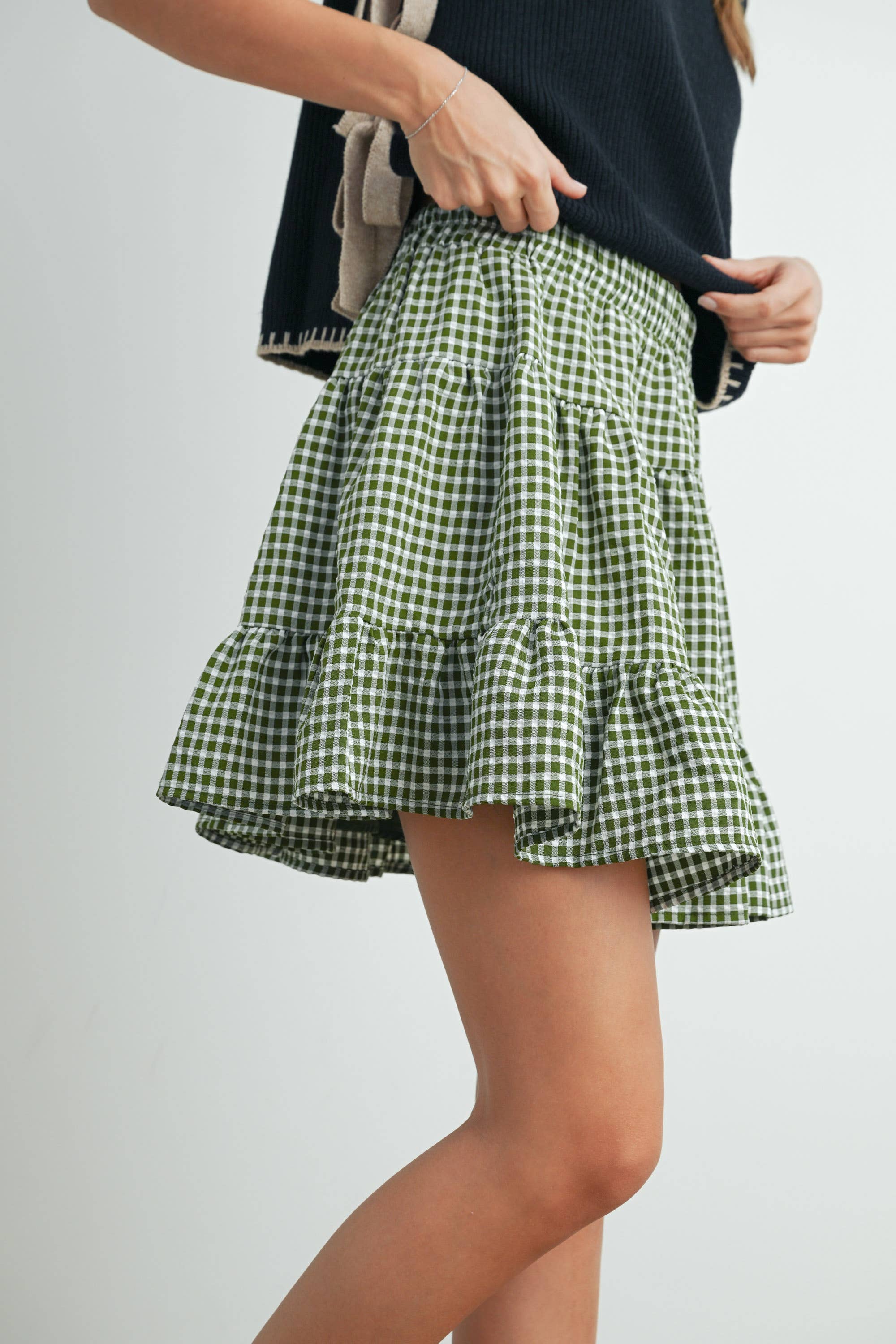 Green checkered mini skirt worn by a person on a plain background. Blackbird Boutique
