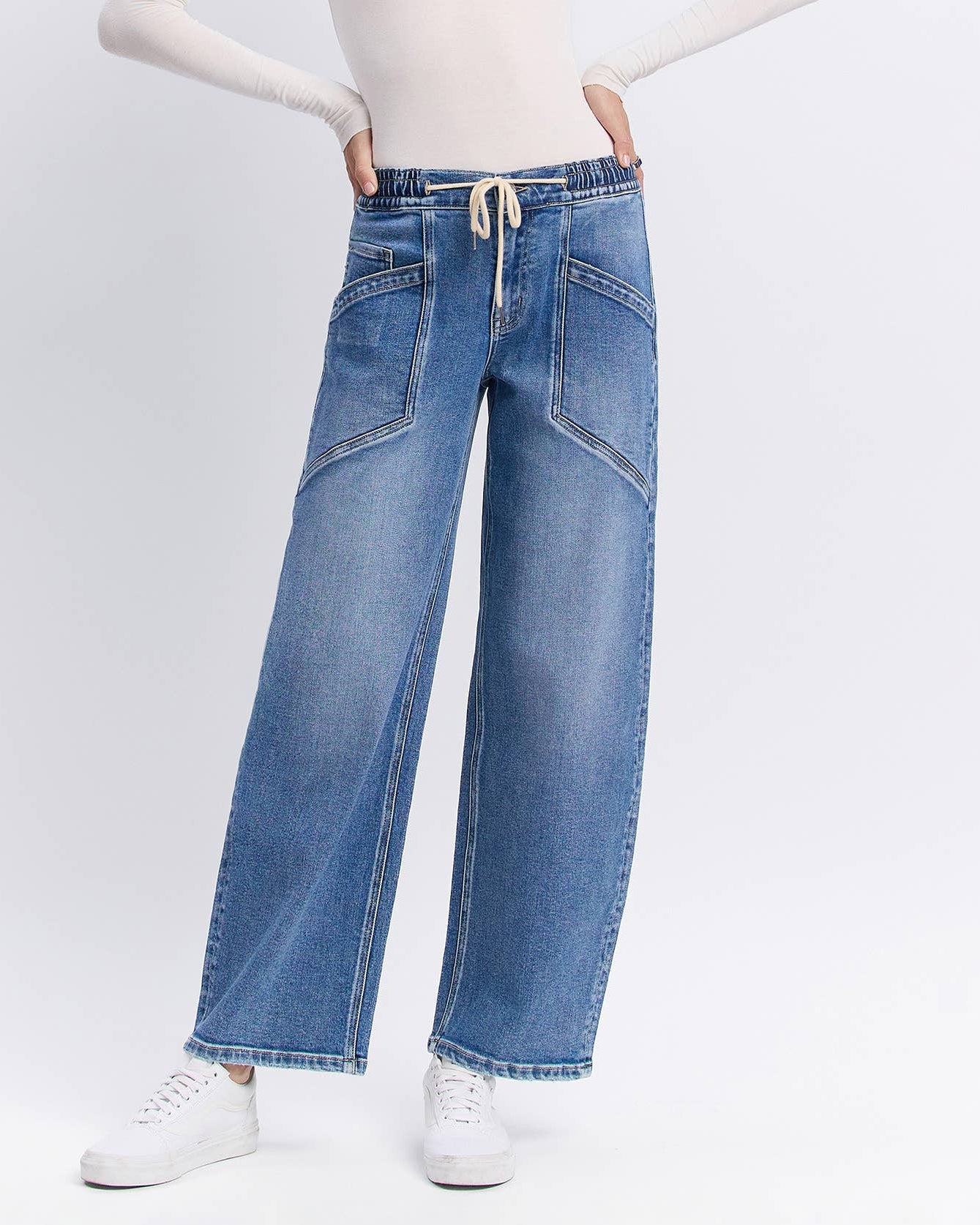 Woman wearing blue jeans and a white top on a white background