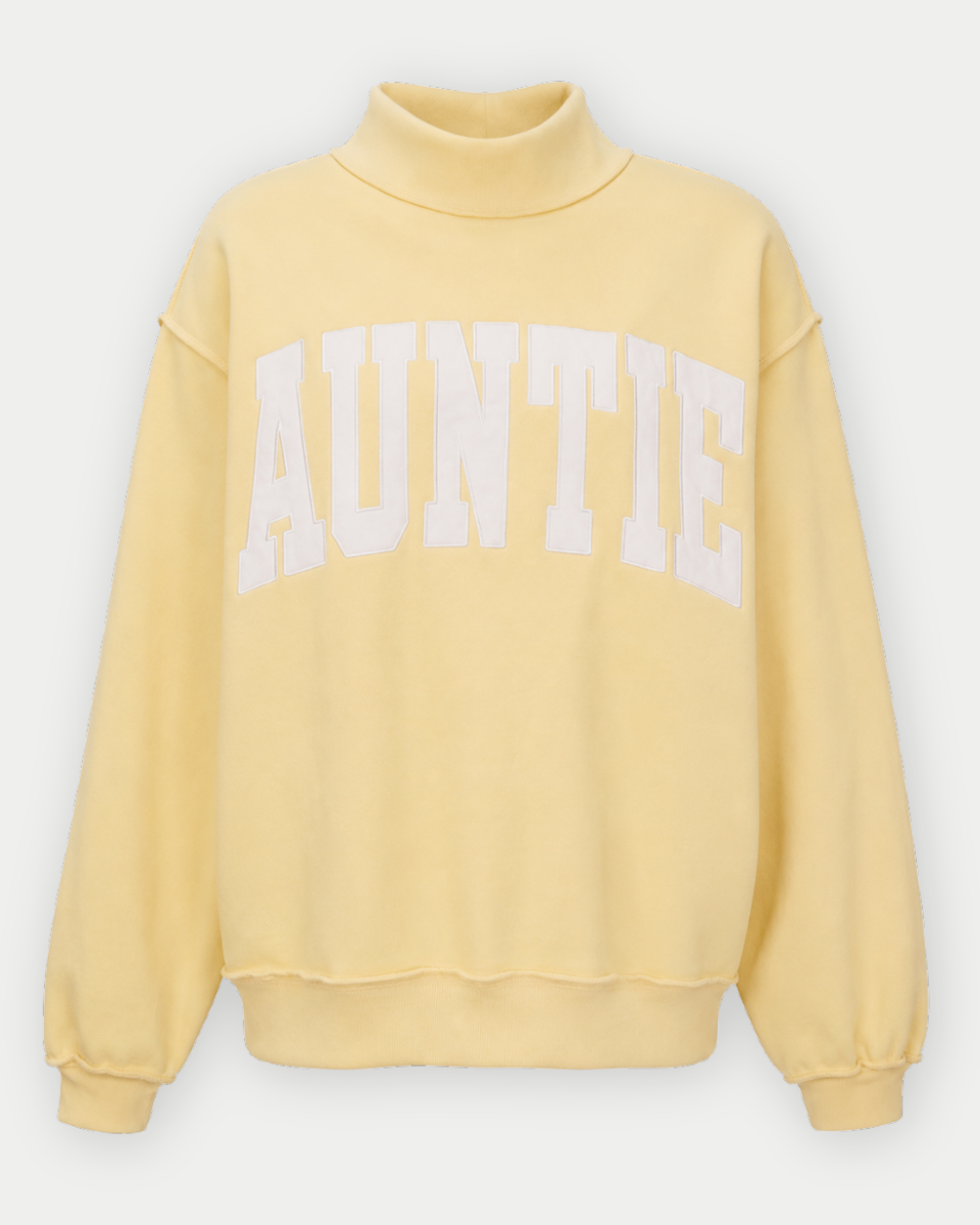 A pale yellow mock-neck sweatshirt with 'AUNTIE' printed in large white varsity-style letters across the chest, displayed on a clean light gray background.