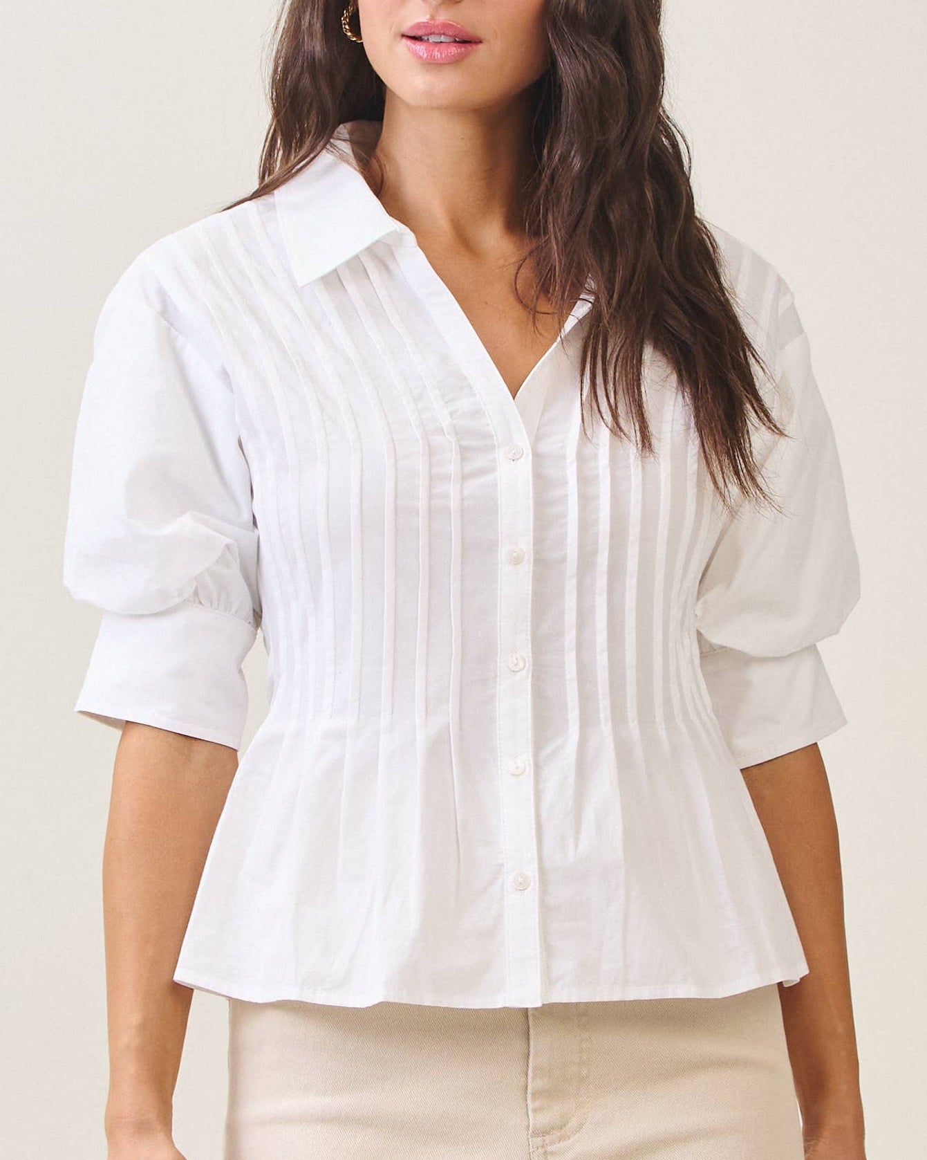 Model wearing a white blouse against a neutral background