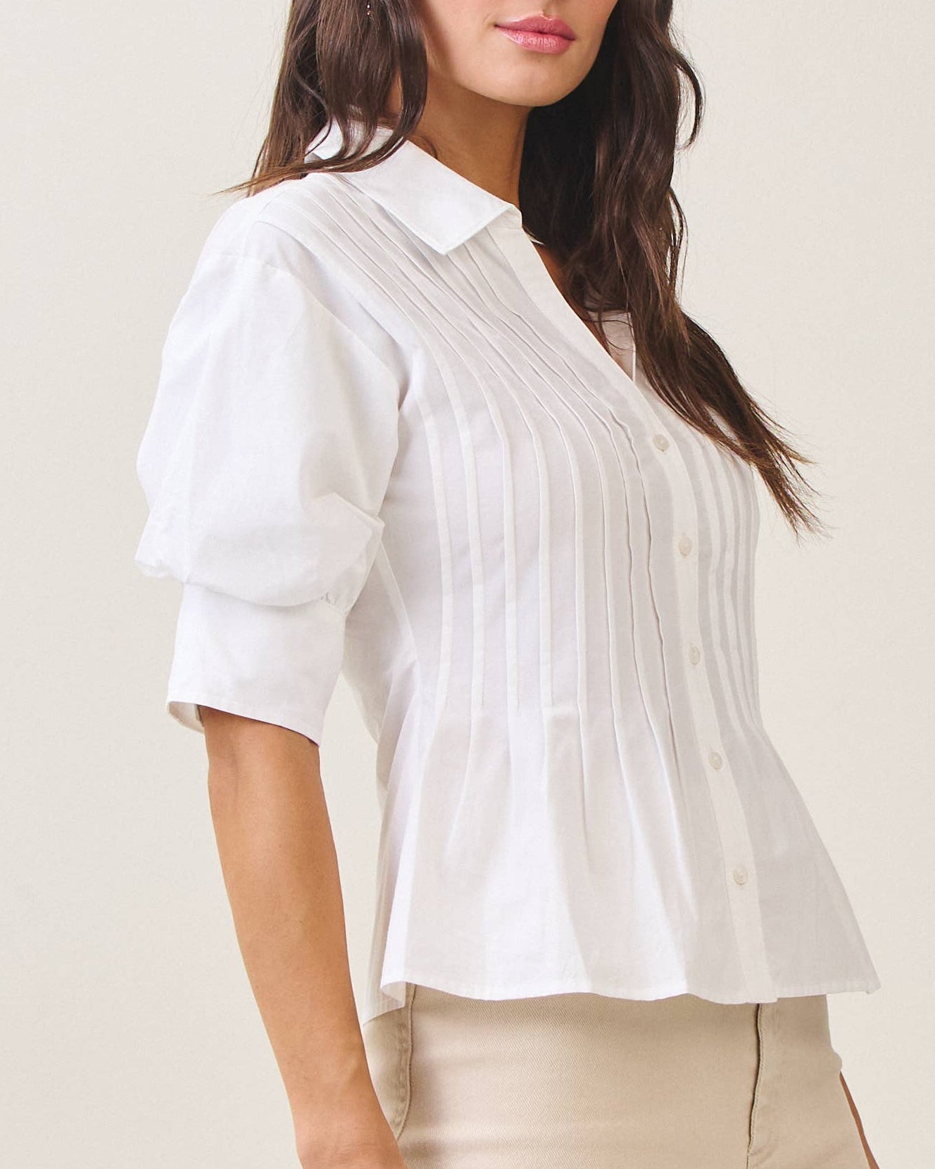 Model wearing a white blouse against a neutral background side view