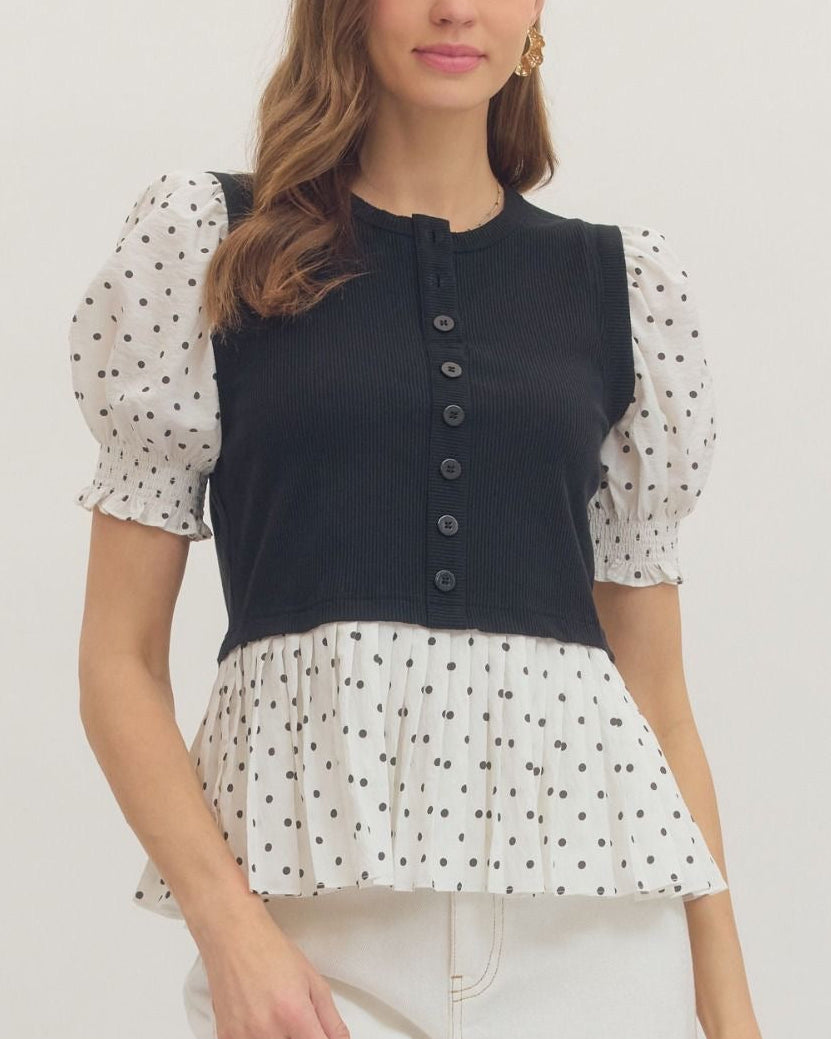 Model wearing a black and white polka dot top with a black bodice on a neutral background