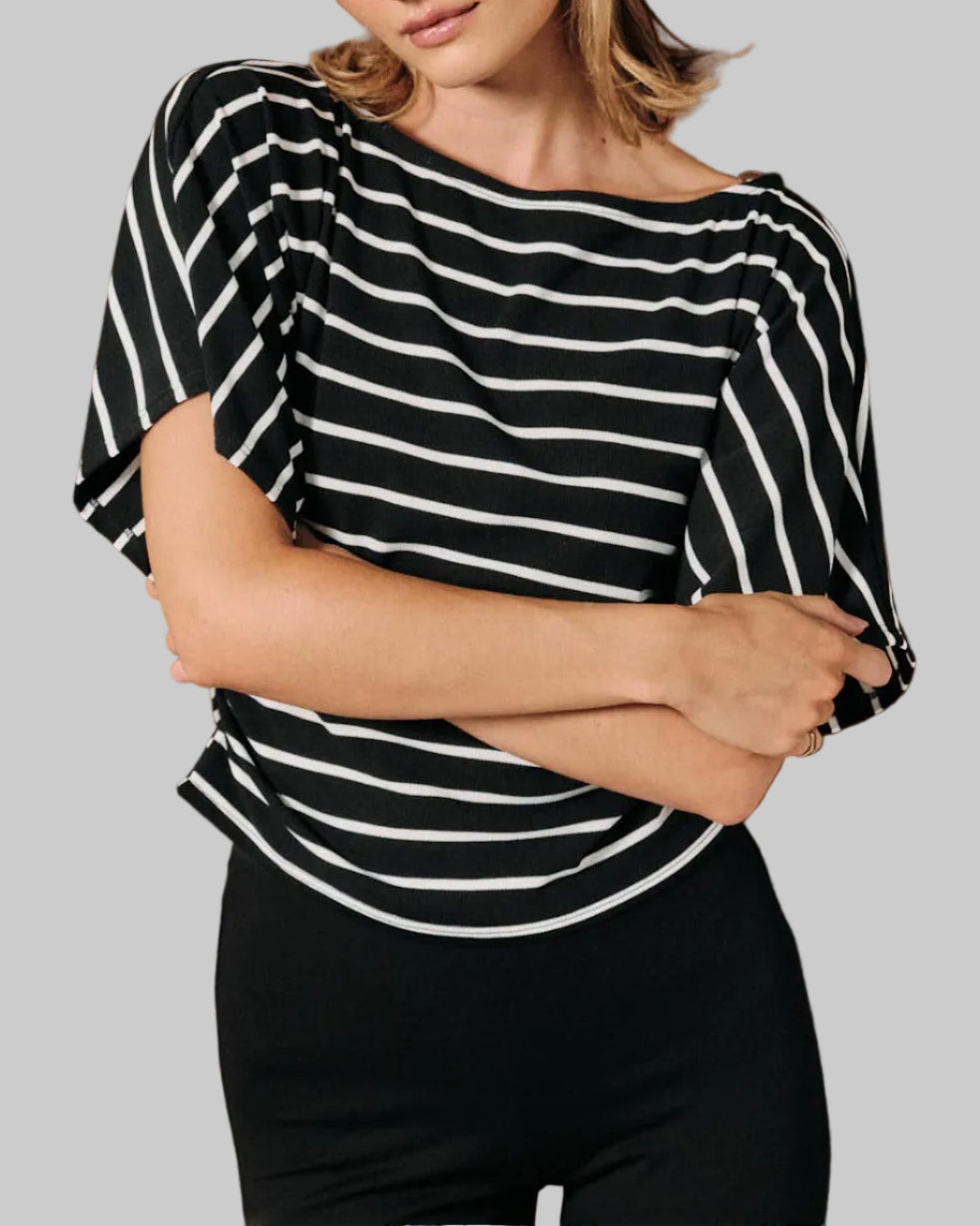 A model wearing a black and white horizontally striped short-sleeve top with dolman sleeves on a neutral background