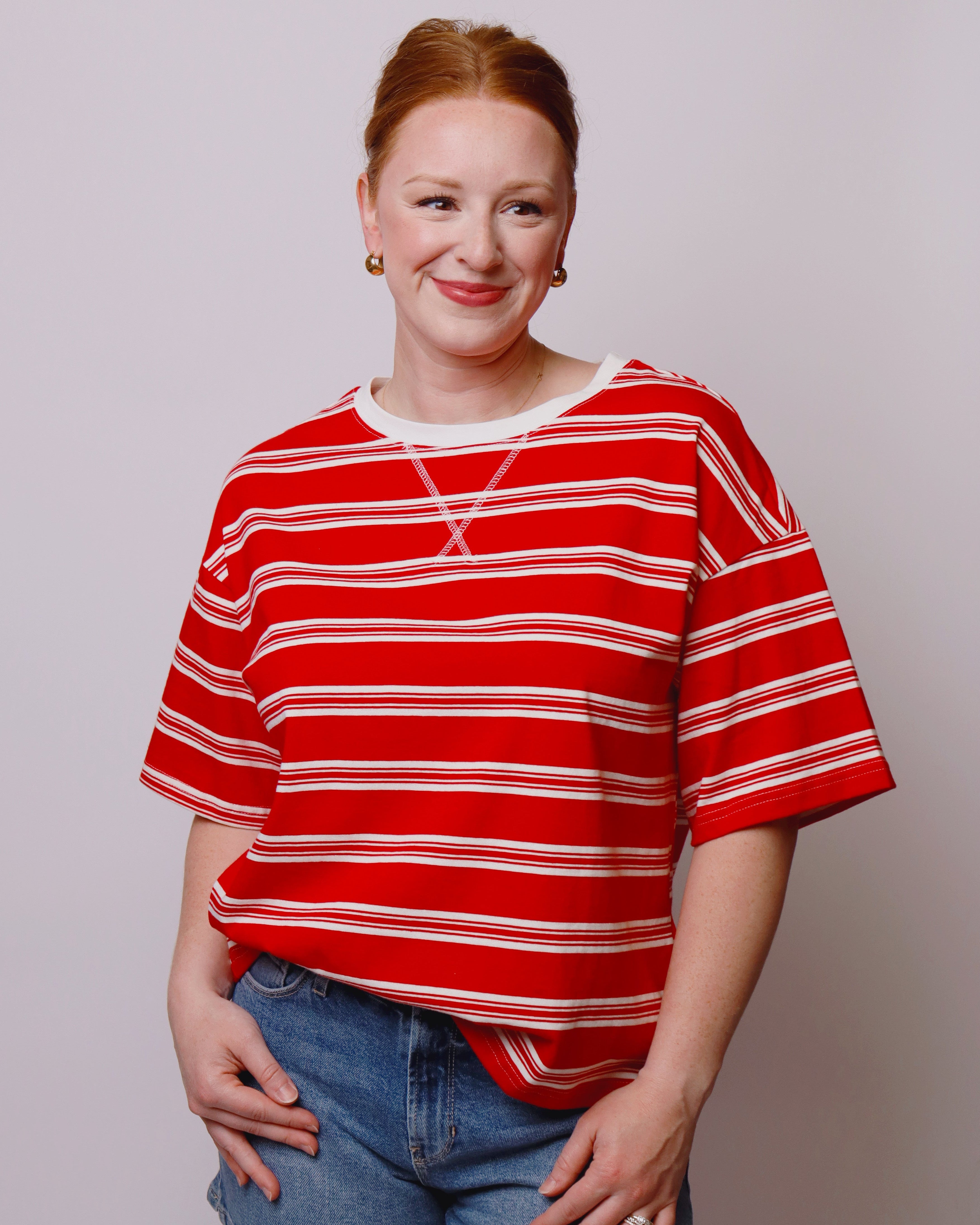 Person wearing a red and white striped shirt and blue shorts against a plain background