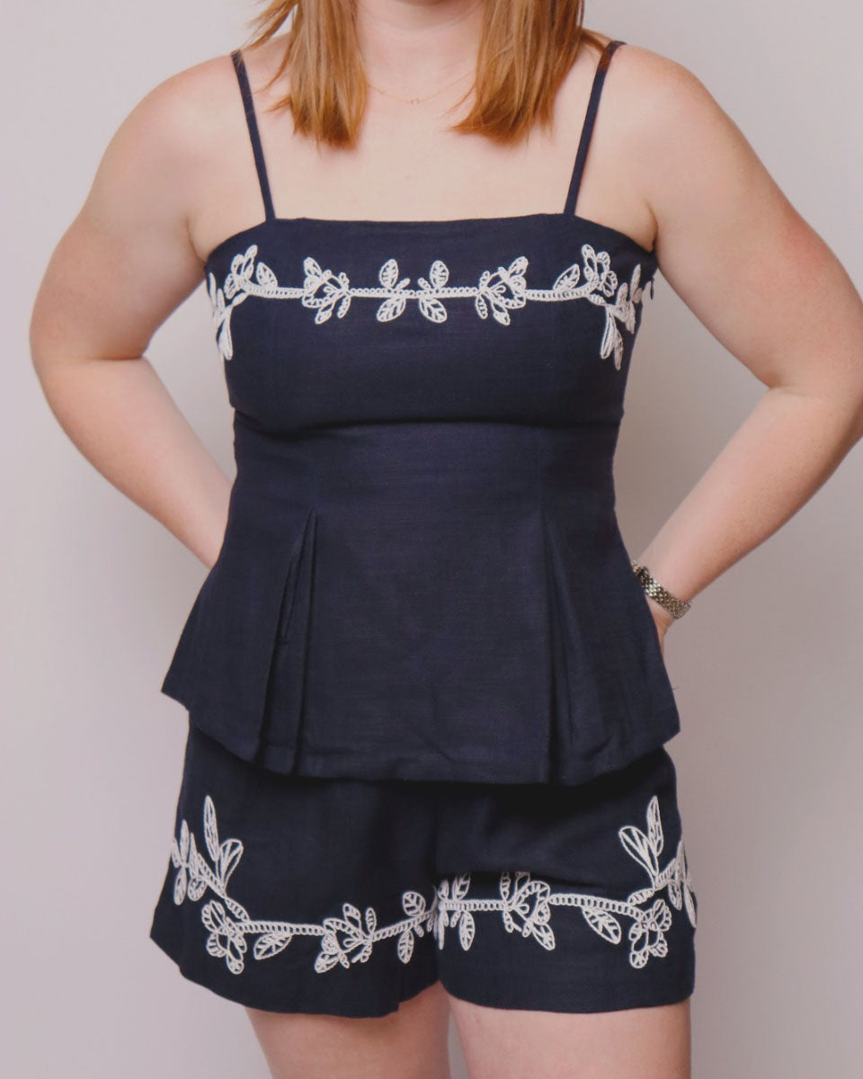 Navy blue top and shorts with white embroidery on a plain background