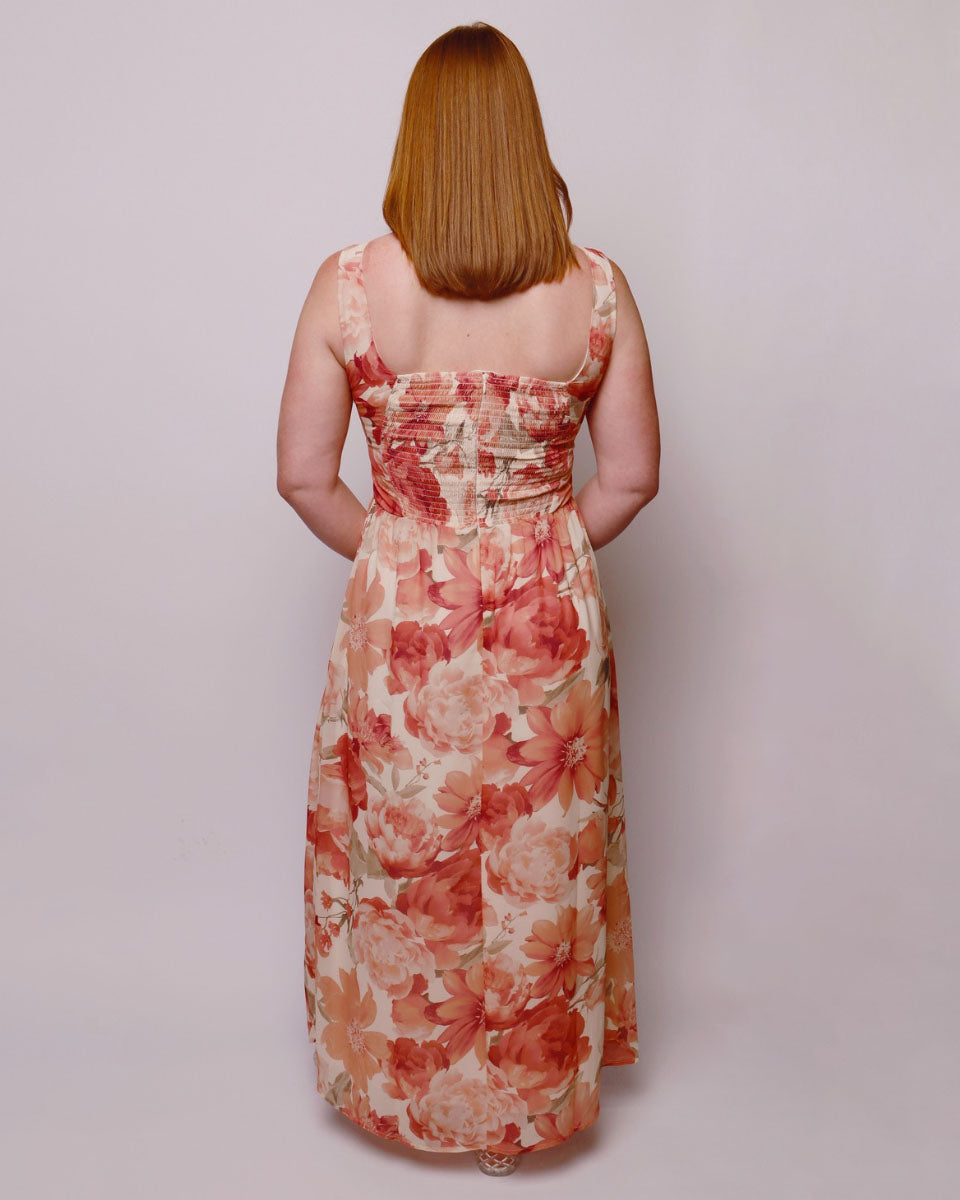 Woman wearing a floral dress with a plain background. Back view