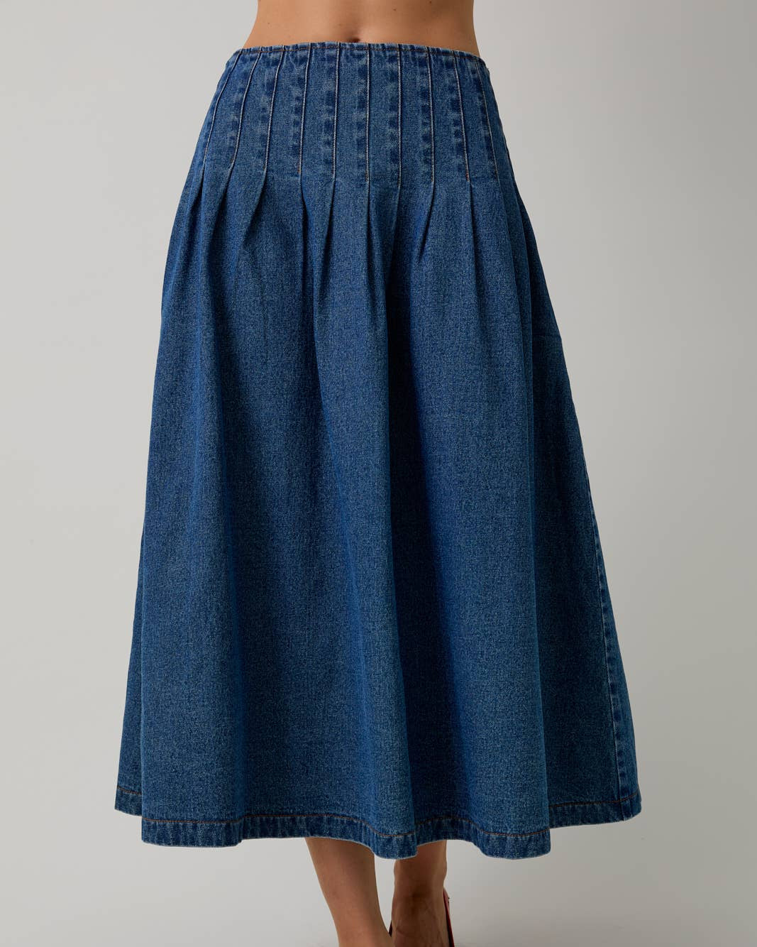 Blue denim skirt worn by a person on a plain background