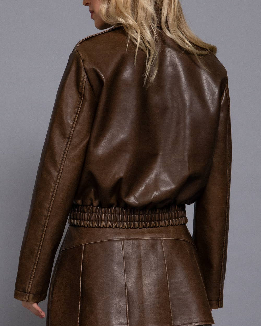 Brown leather jacket and skirt set on a gray background