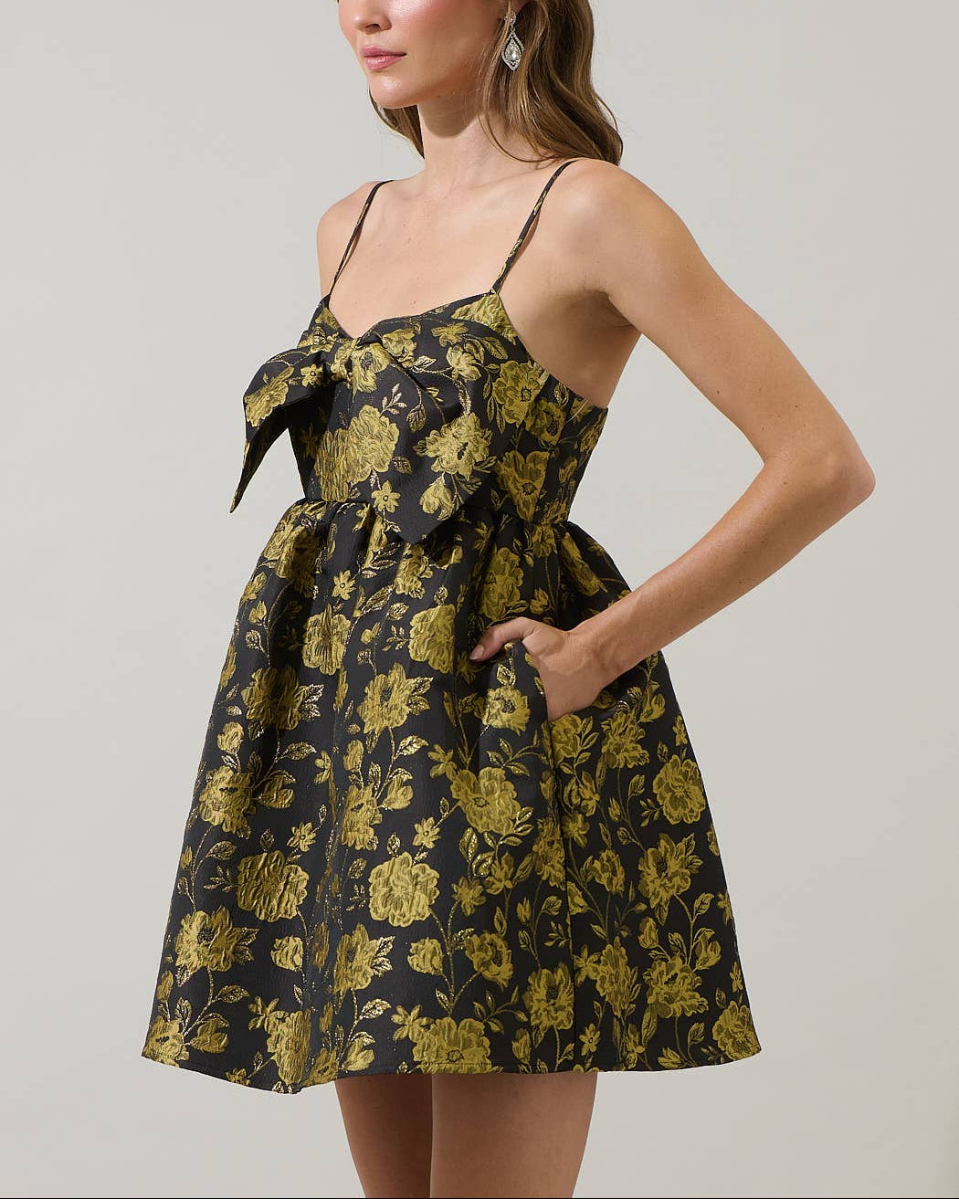 Woman wearing a black floral jacquard dress against a plain background