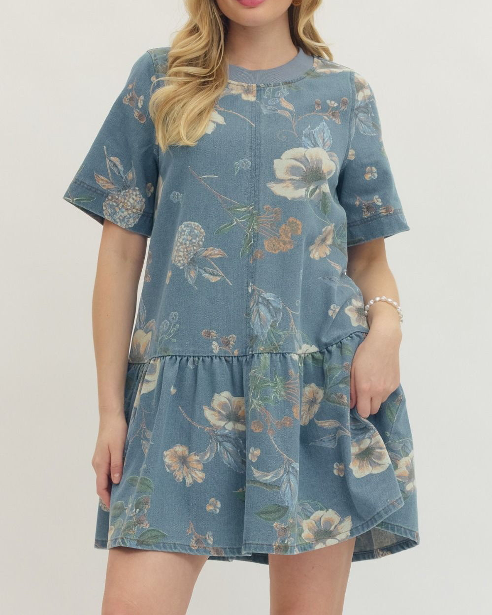 Woman wearing a blue floral dress against a plain background
