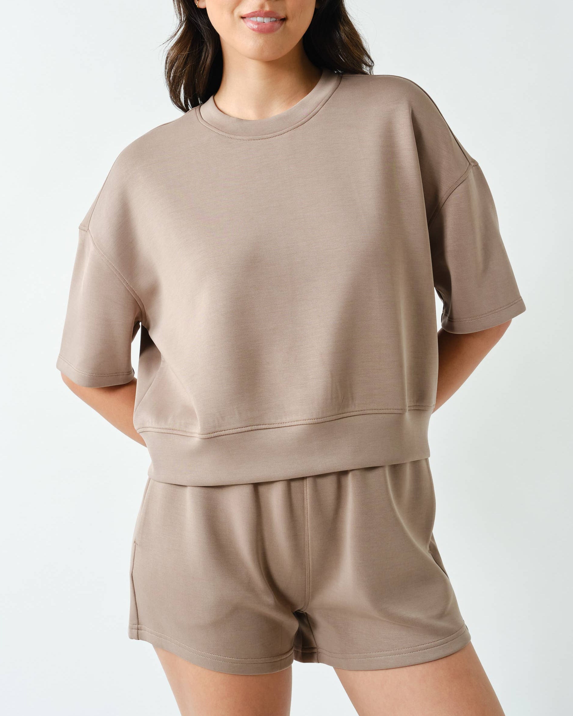 Model wearing a beige shorts set on a neutral background