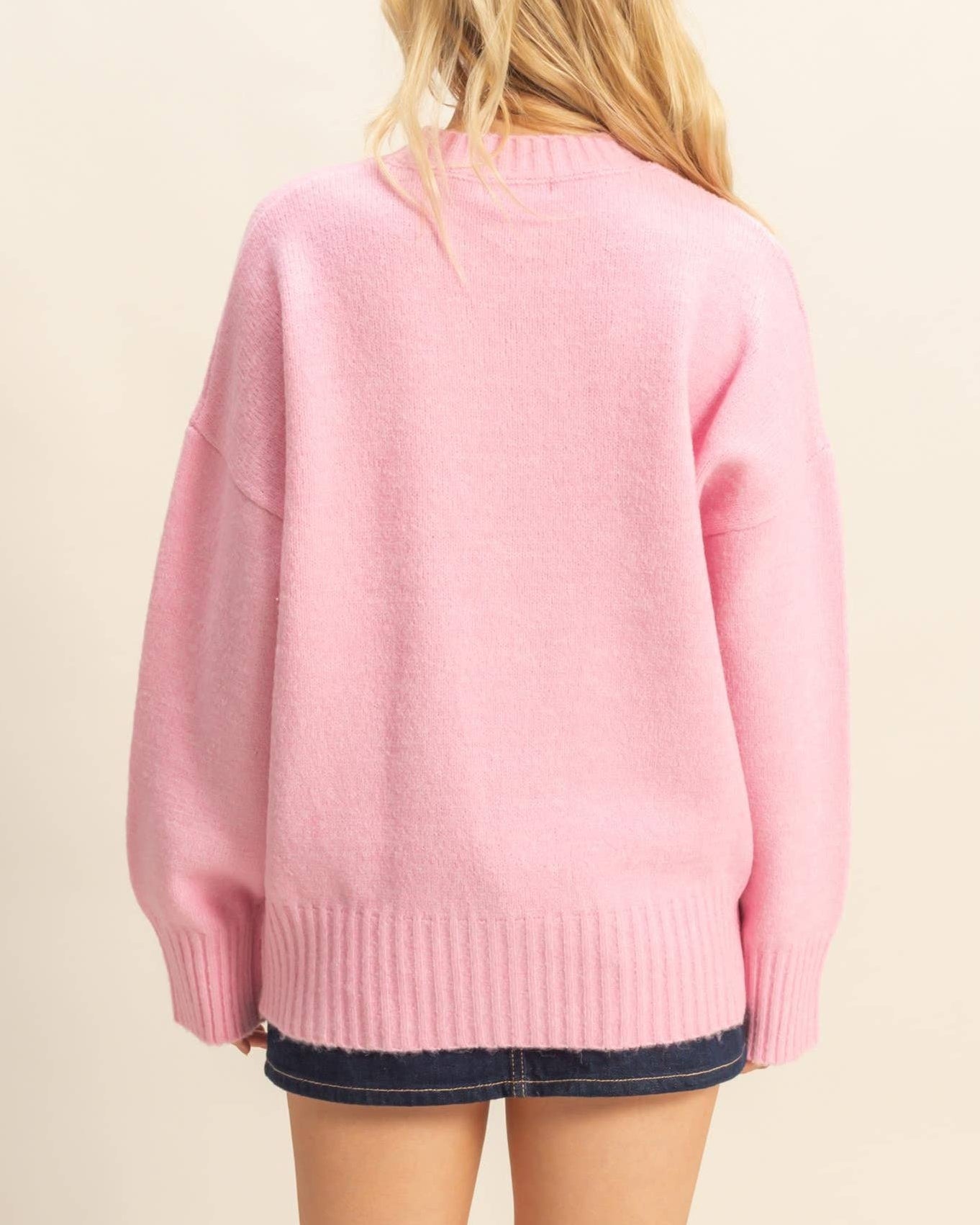 Person wearing a pink sweater on a beige background