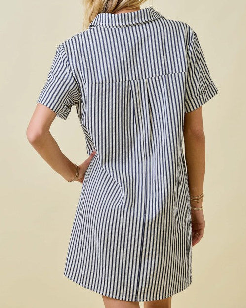 Woman wearing a black and white striped dress against a beige background