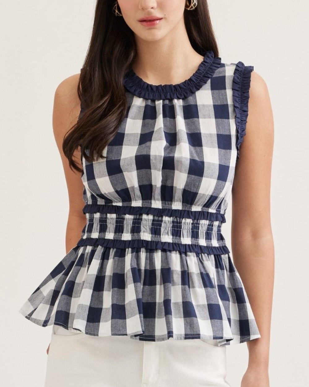 Model wearing a navy and white Gingham peplum top on a neutral background
