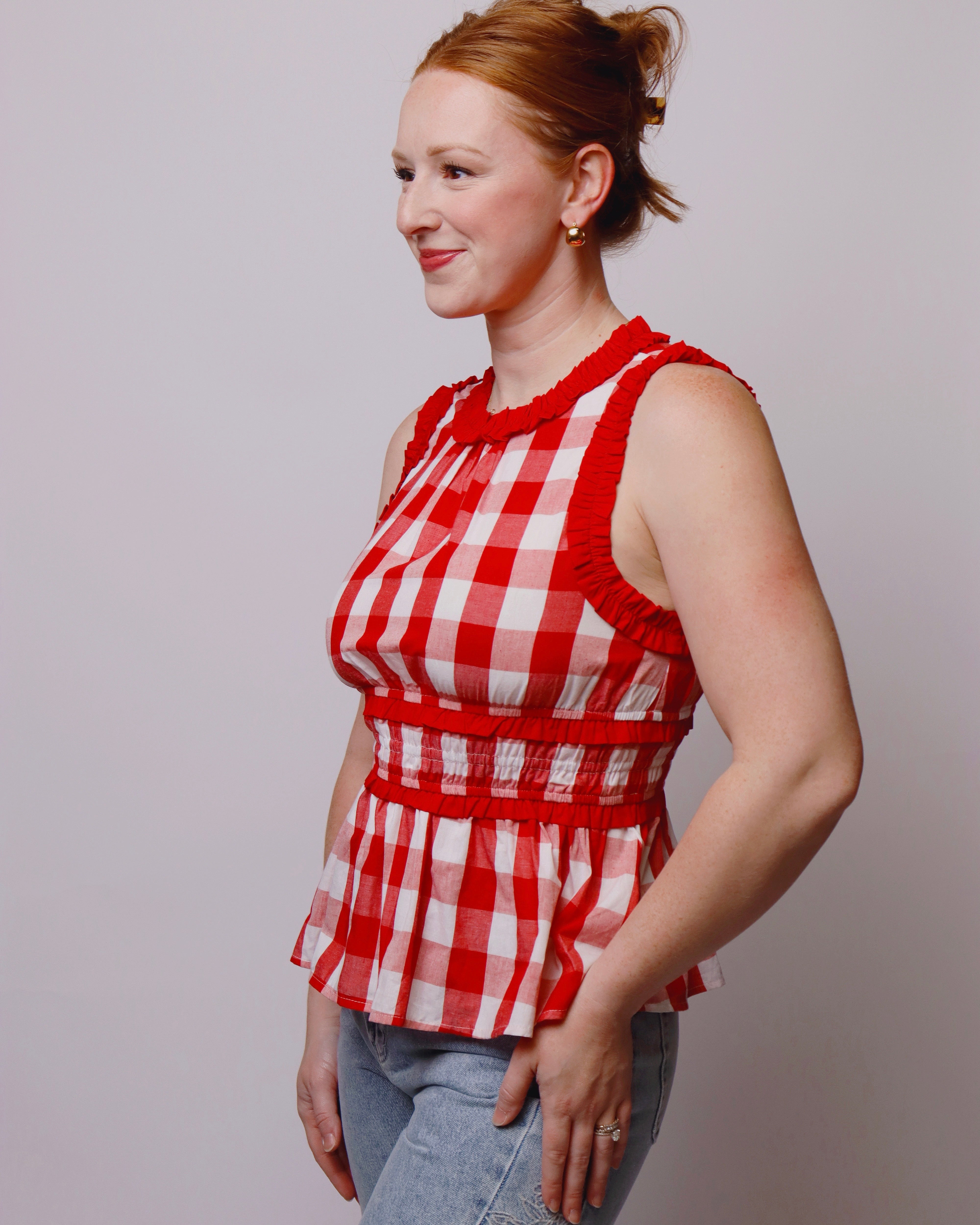 Woman wearing a red and white checkered top against a plain background