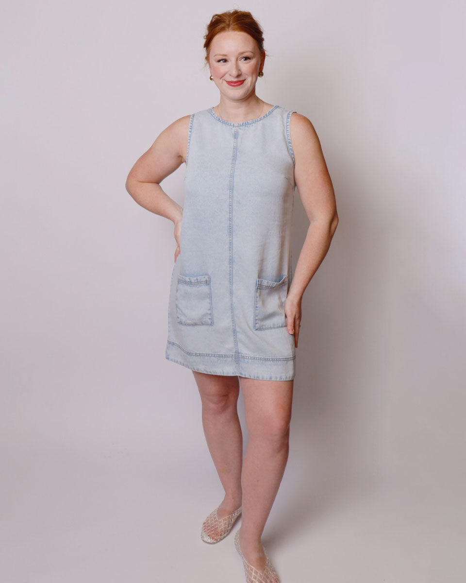 Woman wearing a light blue denim dress against a plain background