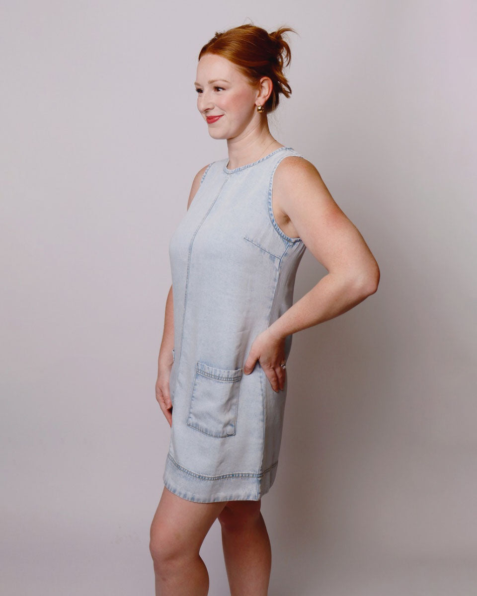 Woman wearing a light blue denim dress against a plain background