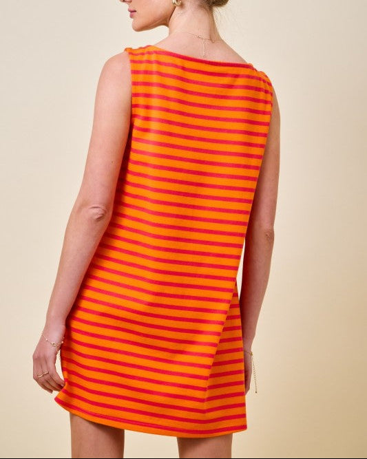 Woman wearing an orange and pink striped mini t-shirt dress on a neutral background back view
