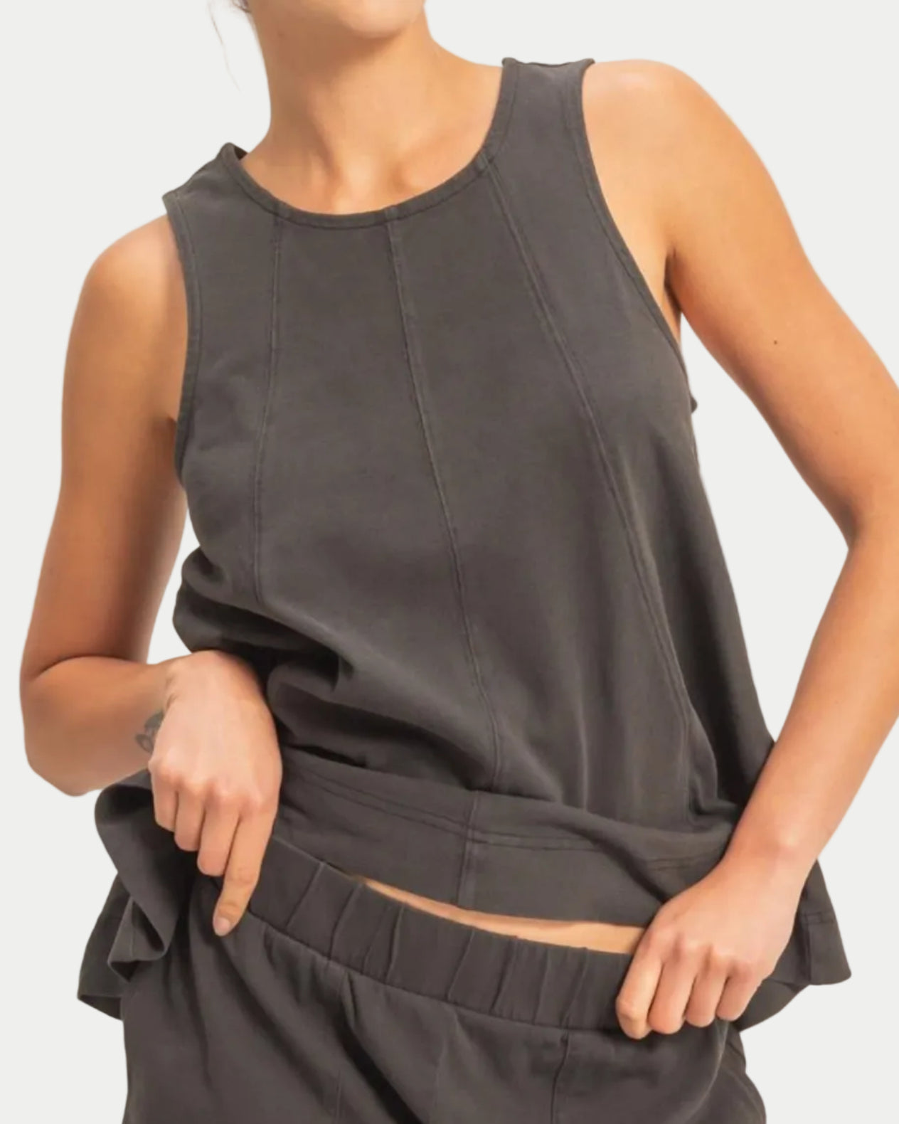 Woman wearing a black sleeveless swing top on a neutral background. front view