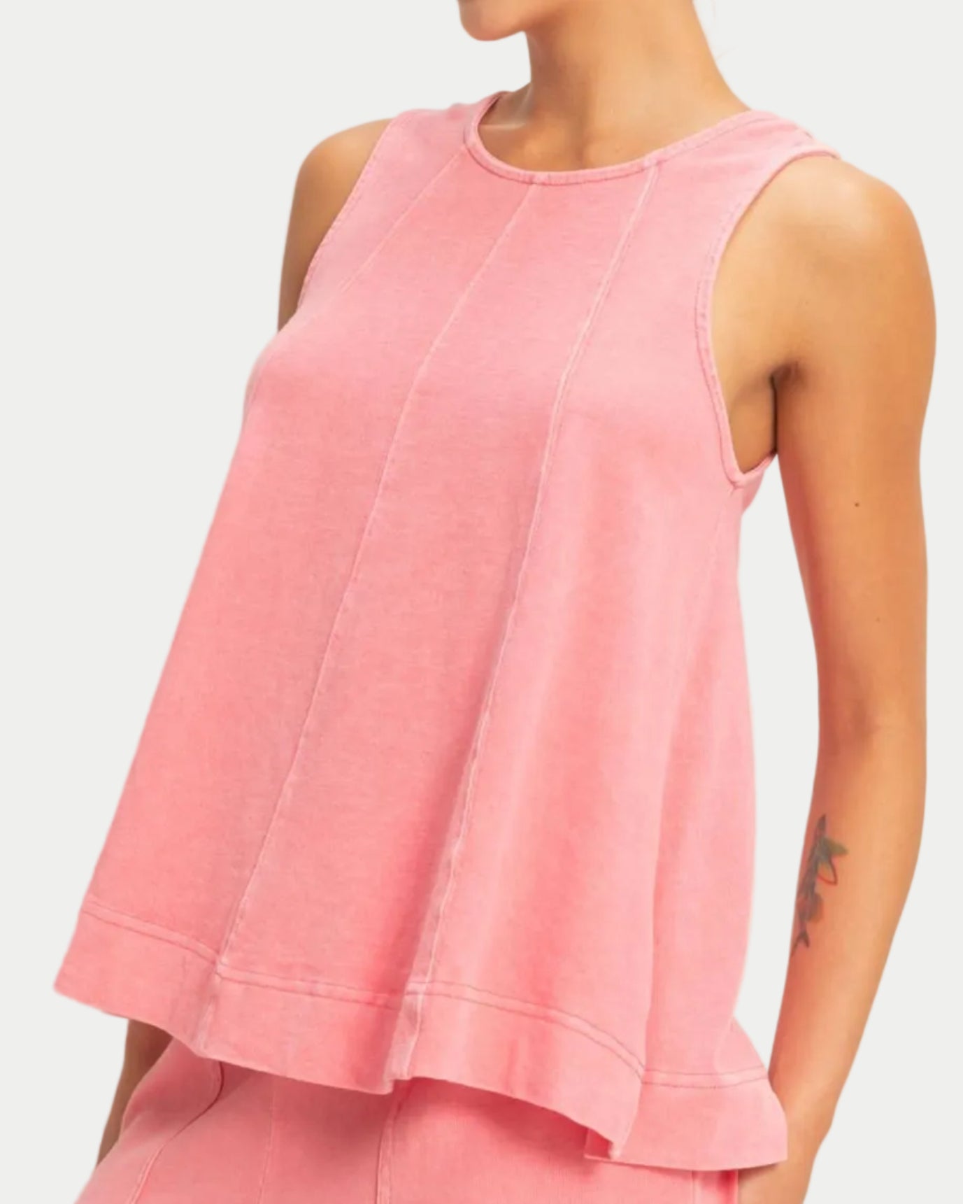 Woman wearing a taffy pink sleeveless swing top on a neutral background. front view