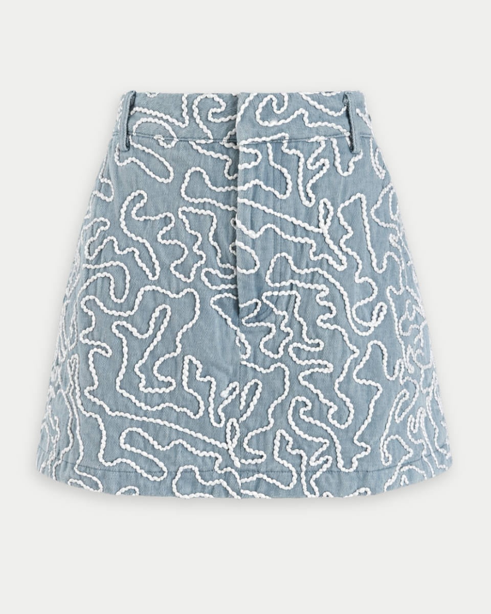 Blue denim skirt with white lace pattern on a light gray background