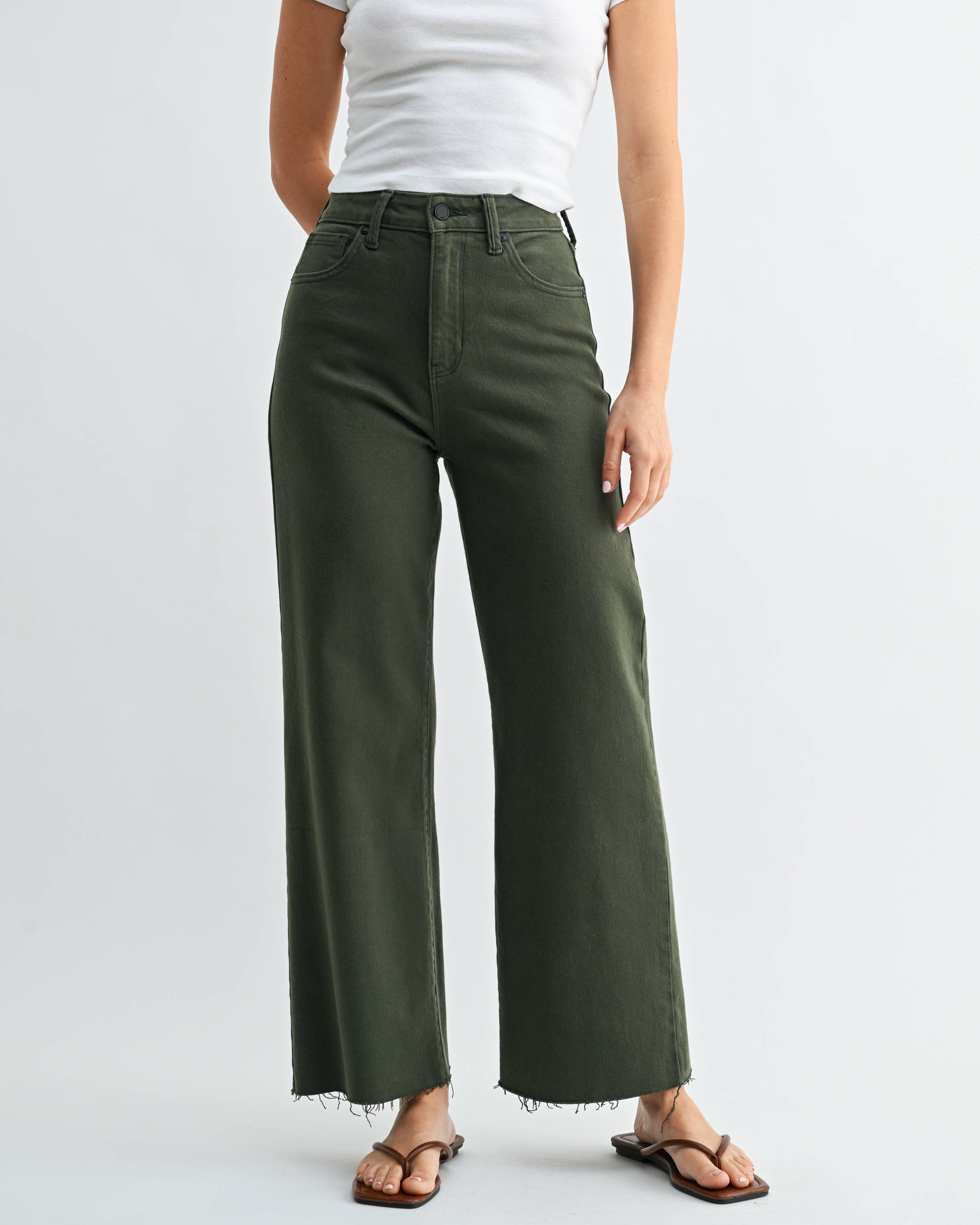 Woman wearing a white t-shirt with red graphics and green wide-leg pants on a white background