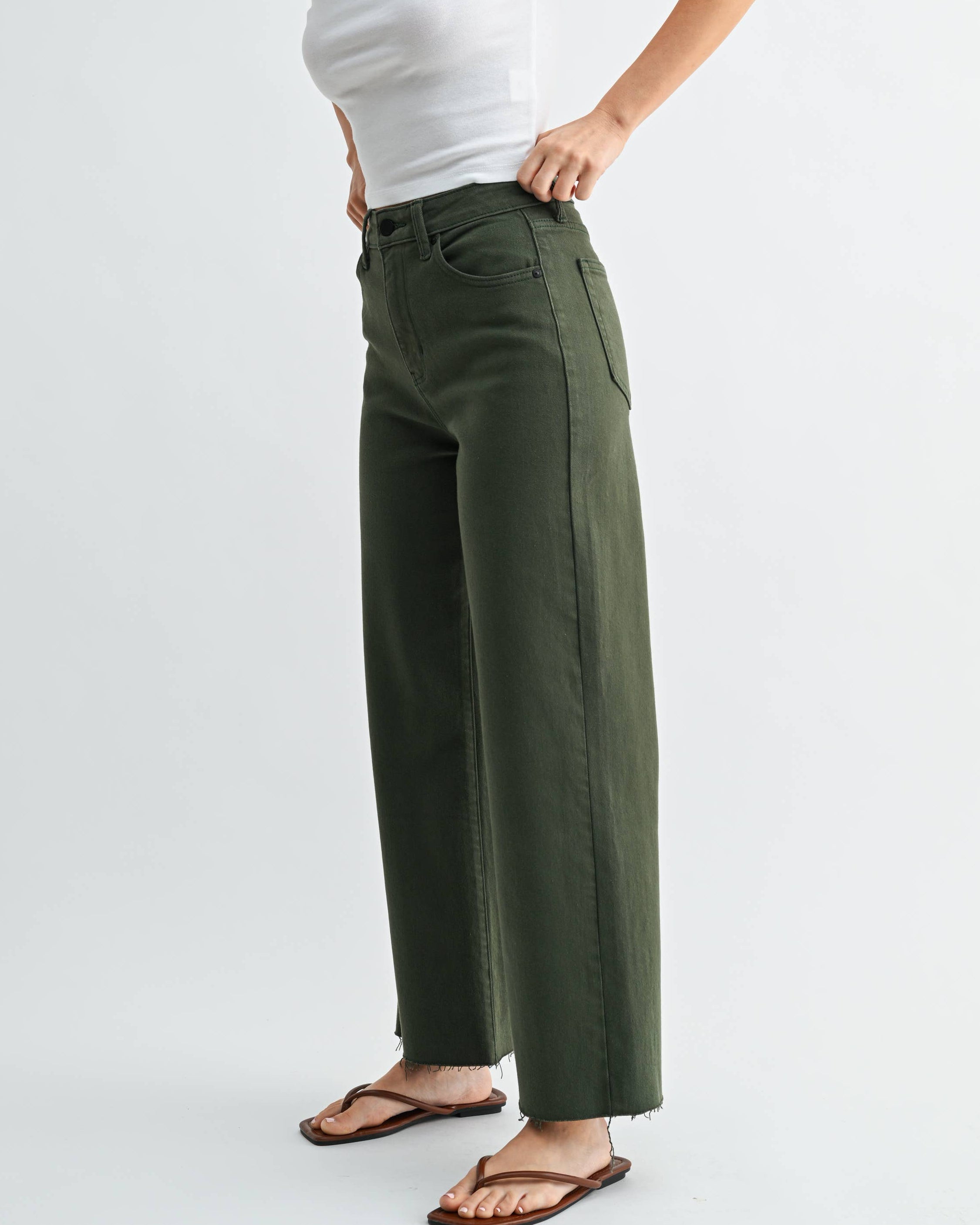 Woman wearing a white t-shirt with red graphics and green pants on a white background
