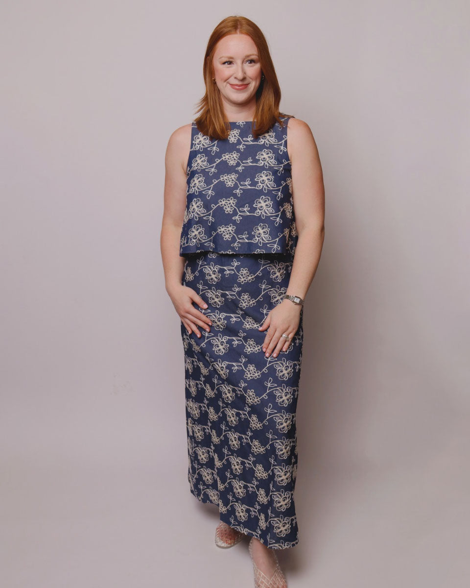 Woman wearing a blue floral dress against a plain background