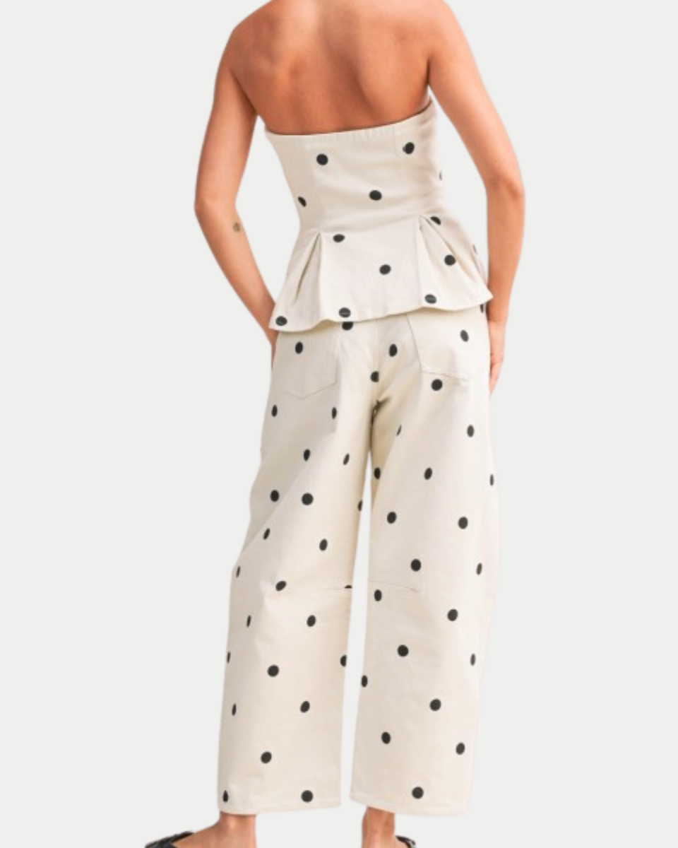 Woman wearing a strapless polka dot jumpsuit on a white background