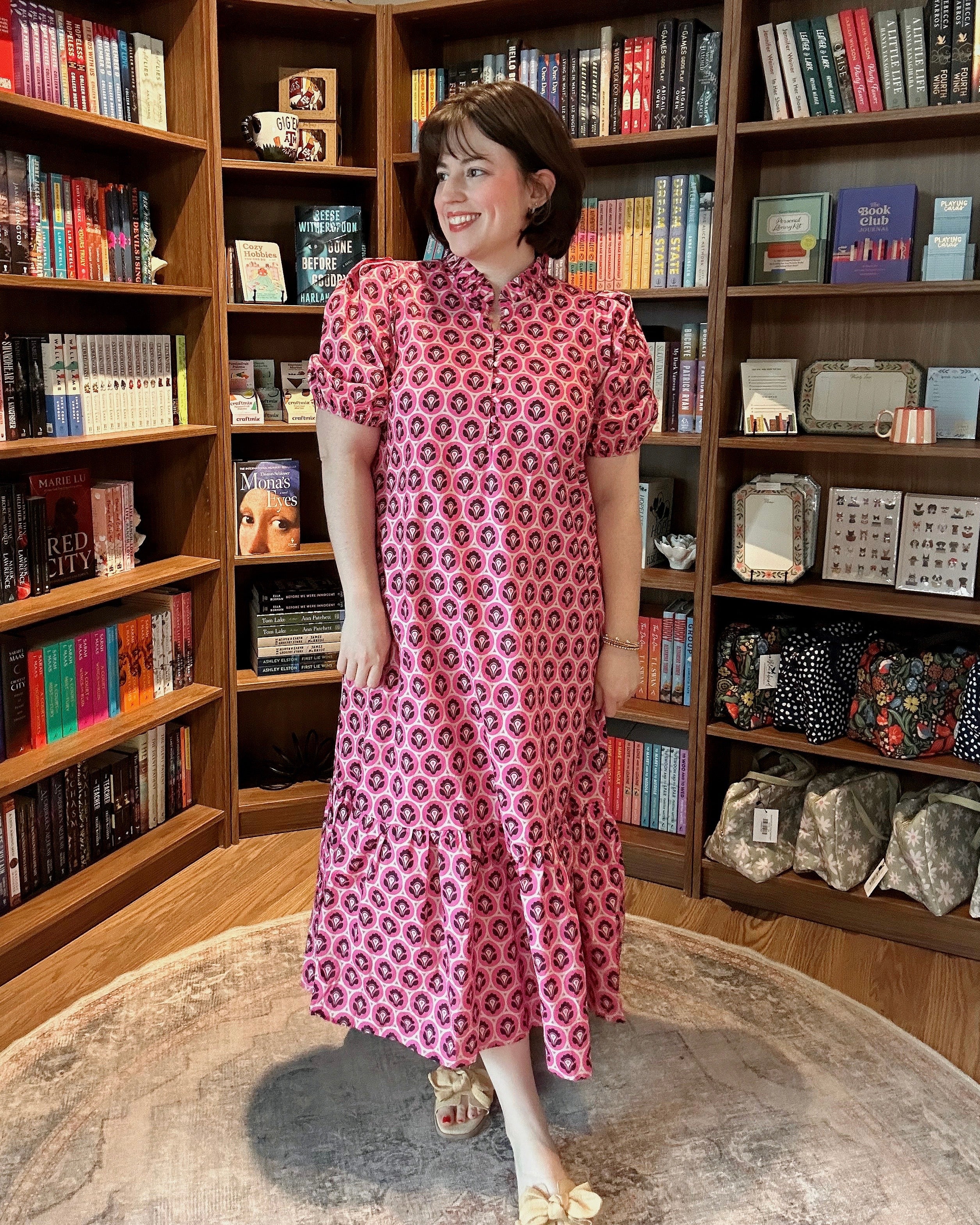 Woman in a pink floral dress standing in a bookstore