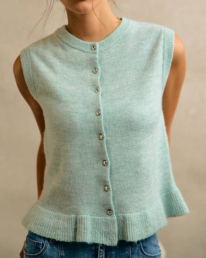 Woman wearing a light blue knitted vest against a beige background
