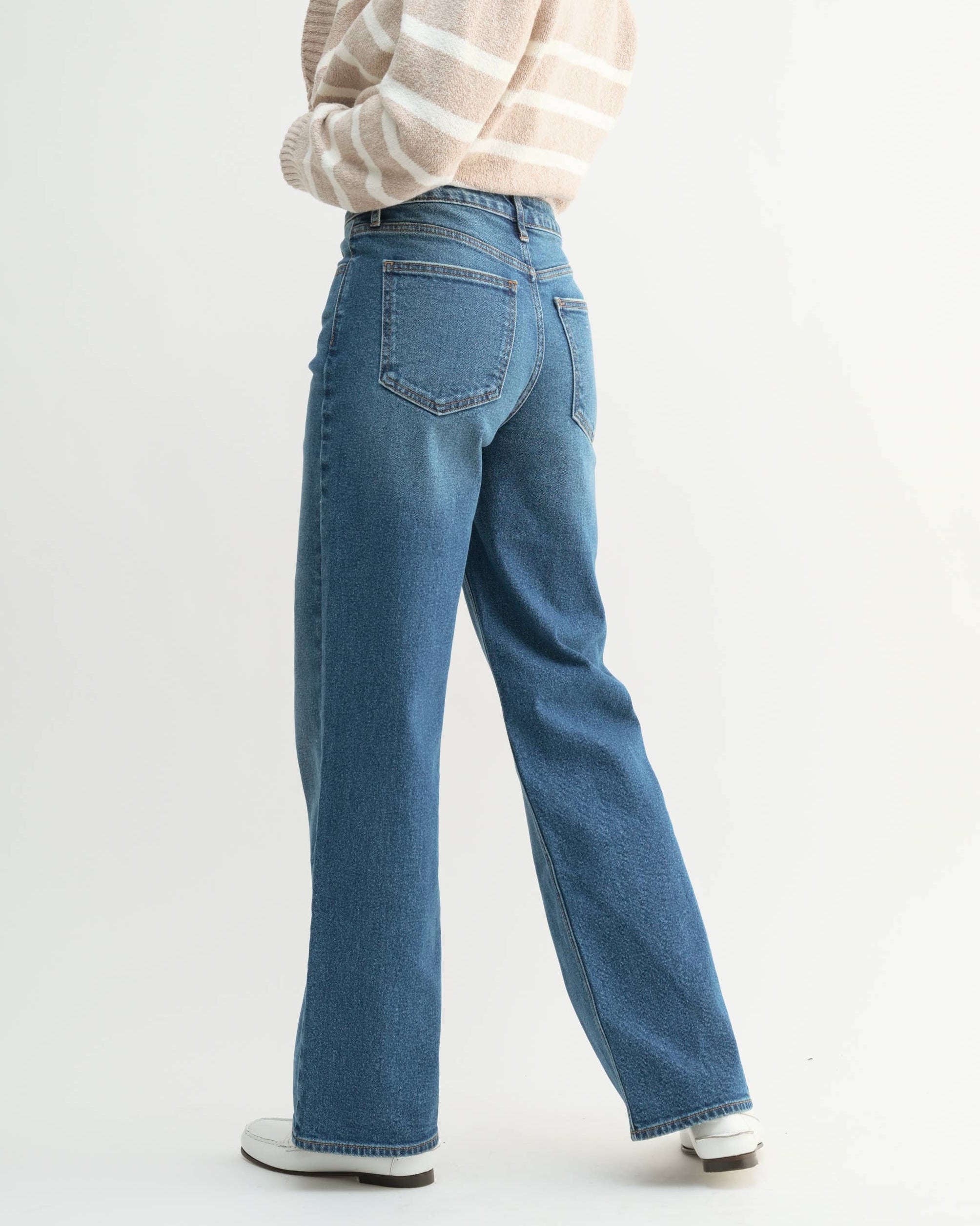 Woman wearing a striped sweater and blue jeans on a white background
