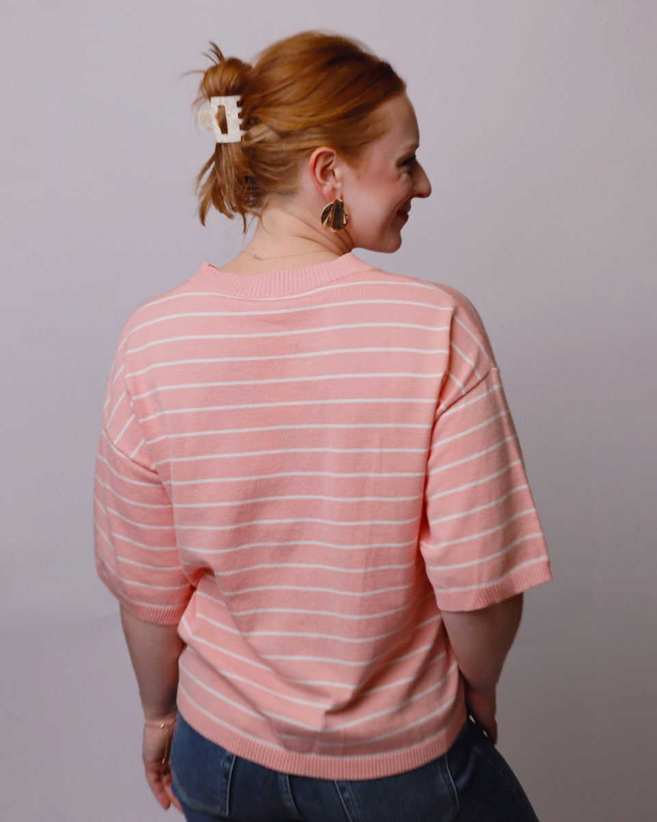 Person wearing a pink striped sweater against a plain background