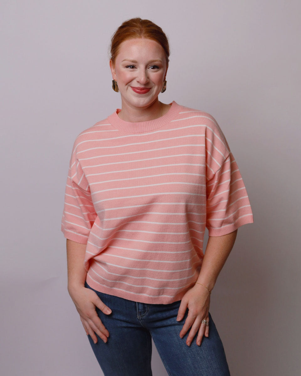 Woman wearing a pink striped shirt against a plain background