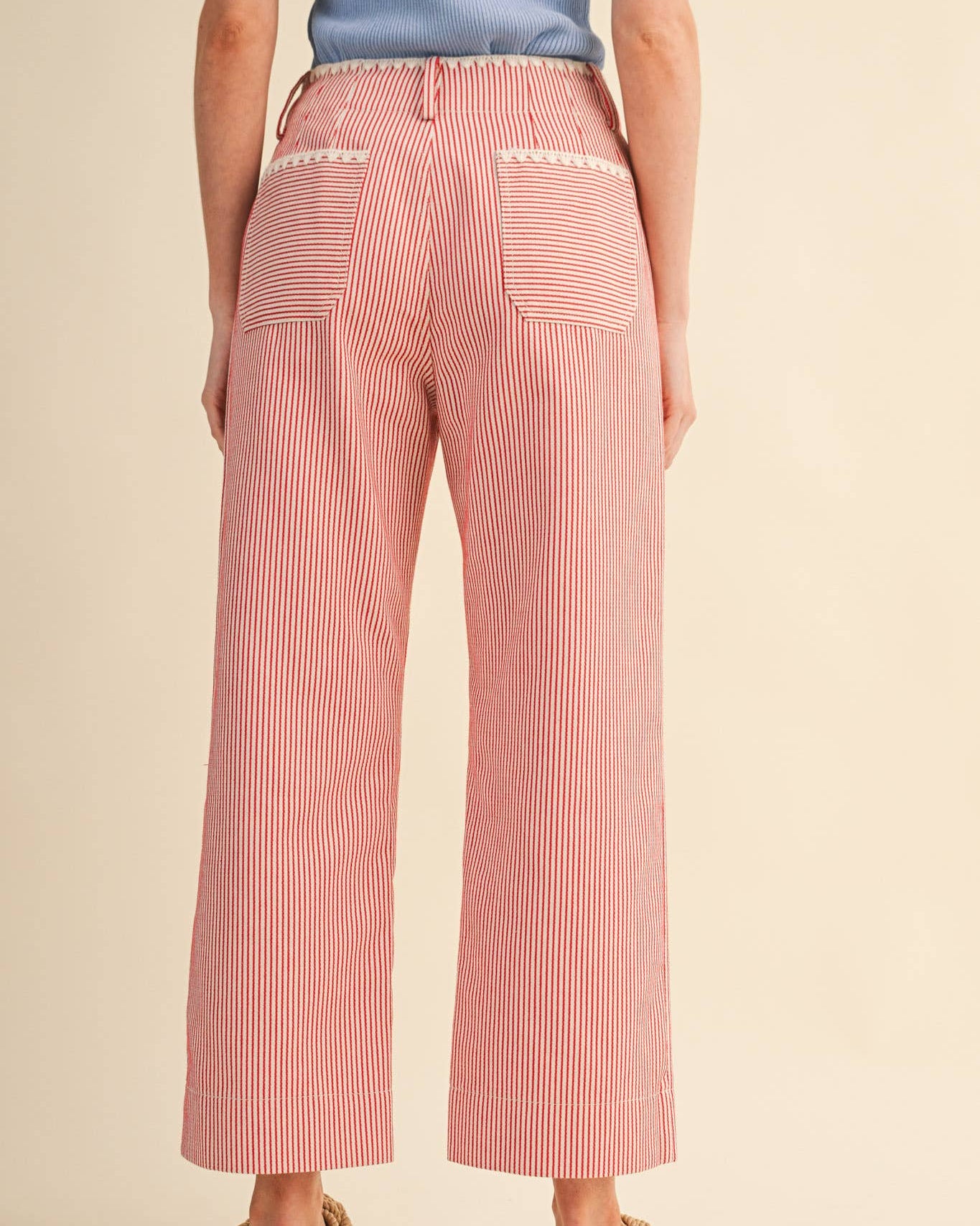 Person wearing red striped pants on a beige background back view