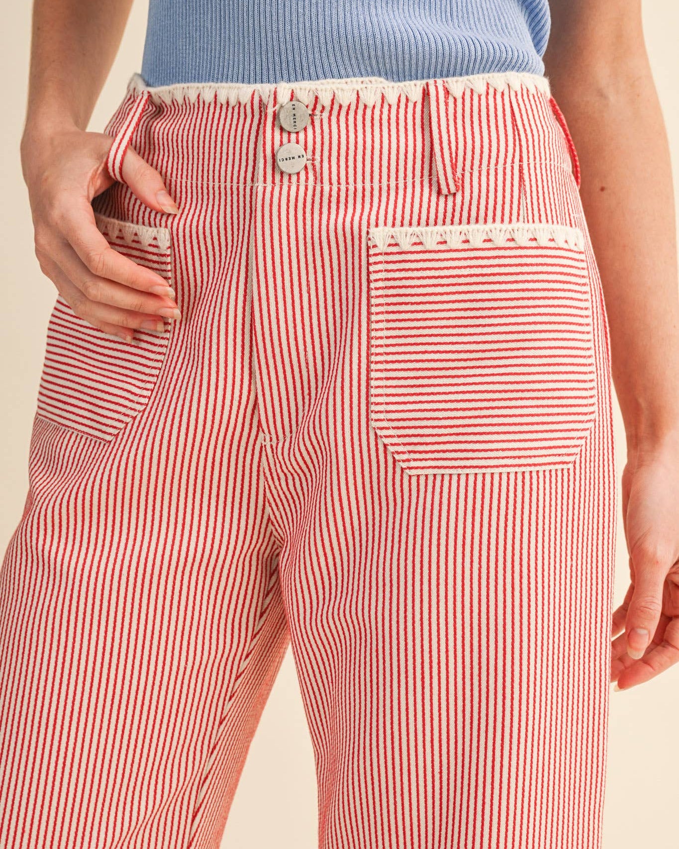 Red and white striped pants worn by a person on a beige background close up