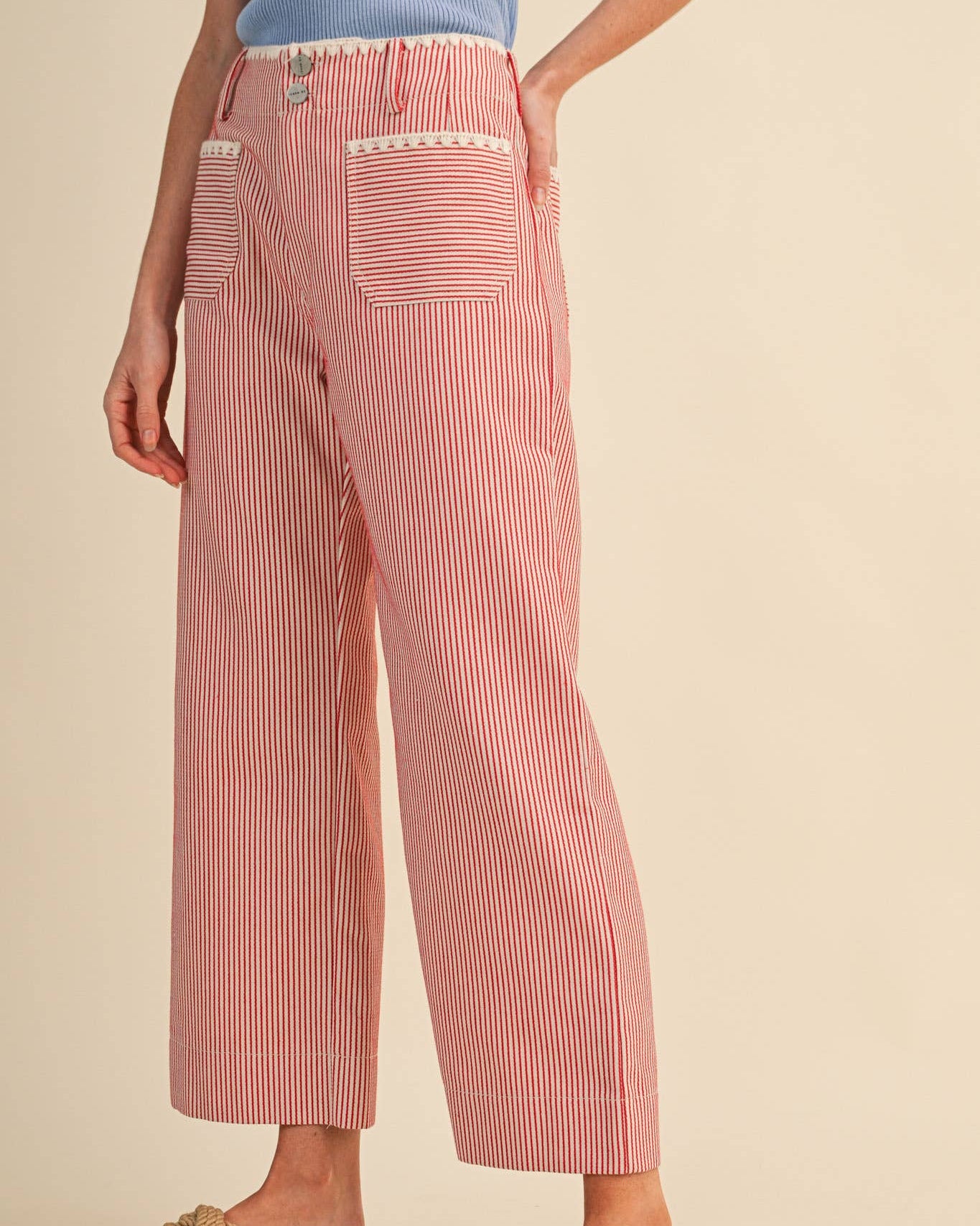 Person wearing red and white striped pants on a beige background side view