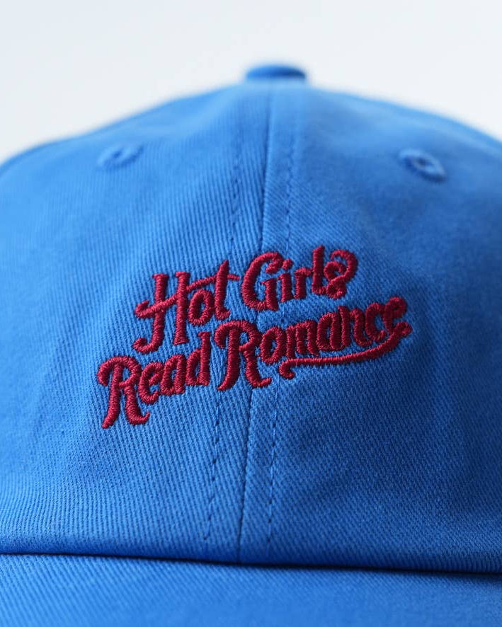 Blue cap with red text 'Hot Girls Read Romance' on a light blue background