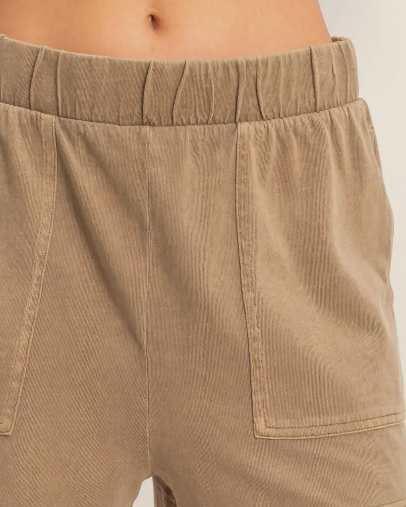 Beige shorts worn by a person on a white background
