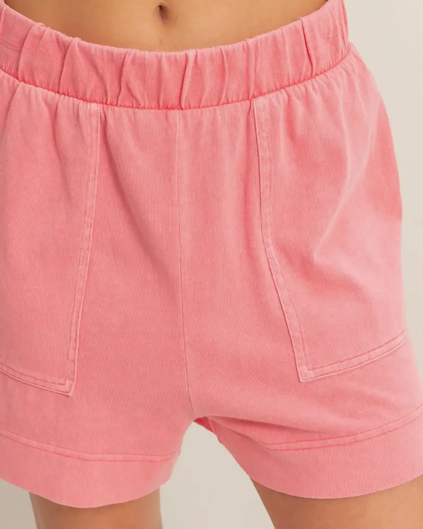 Pink shorts worn by a person on a plain background