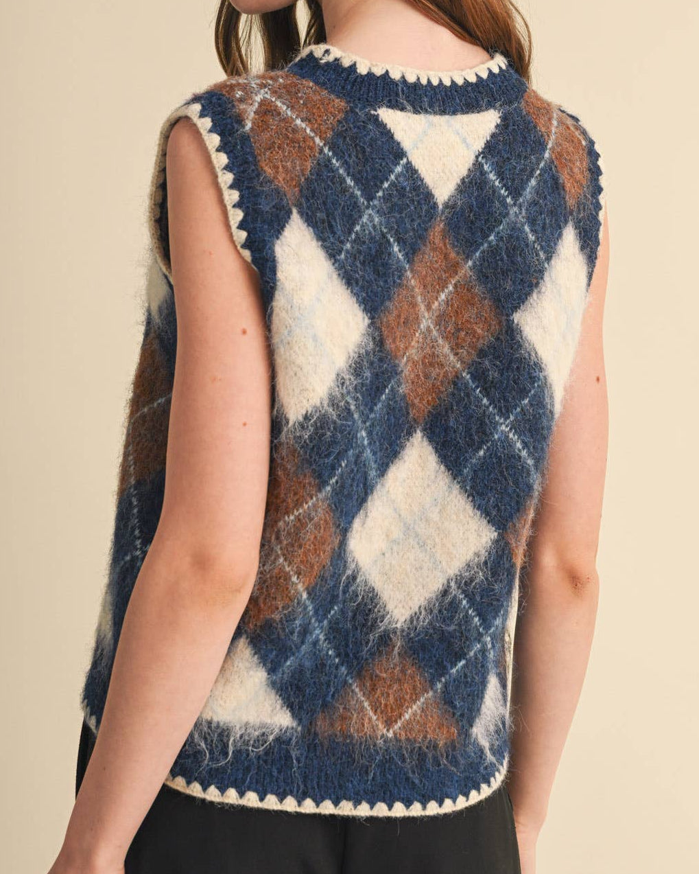 Model wearing a navy and brown argyle sweater vest on a neutral background