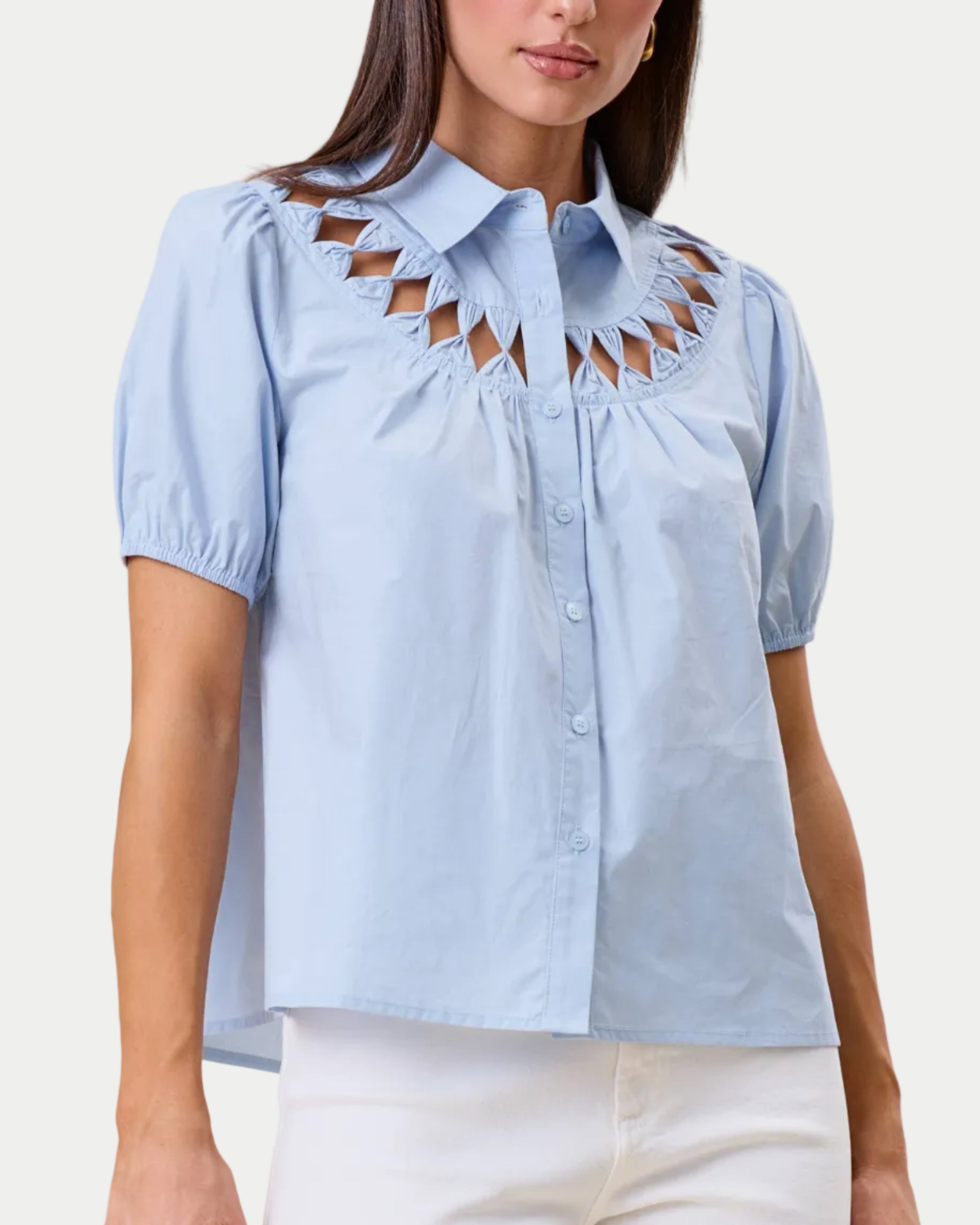 Cutwork blouse. Sky blue on a model with a neutral background. Cutout detail around the neckine. Front view