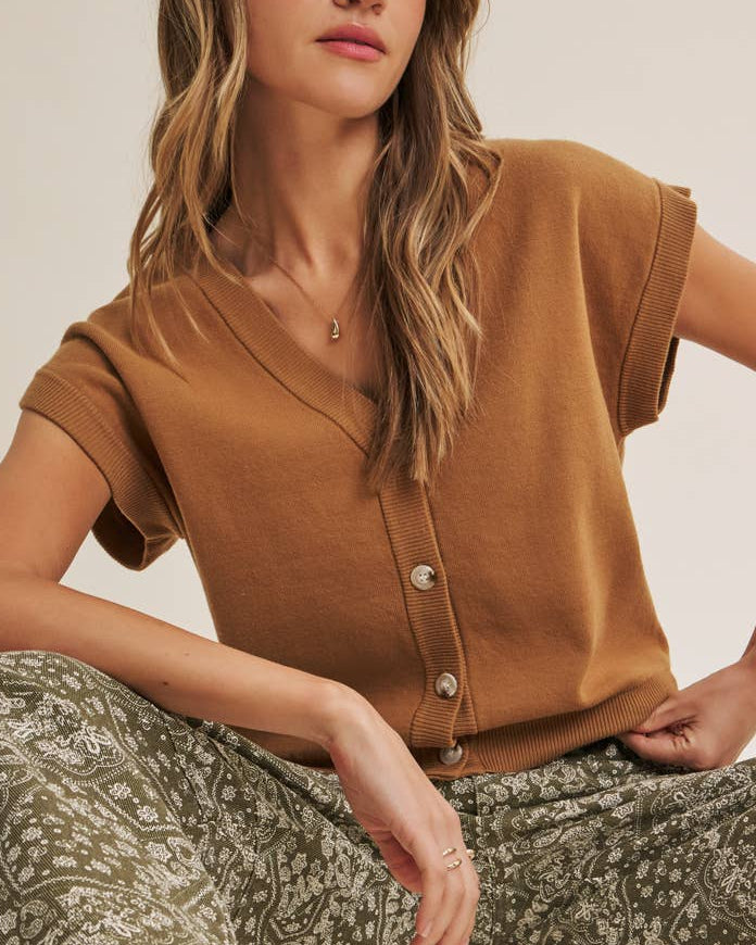 Woman wearing a brown sweater vest cardigan on a neutral background