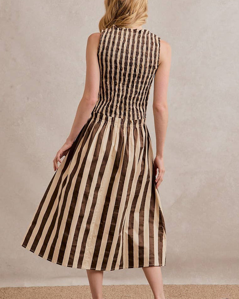 Woman wearing a brown and beige striped dress against a neutral background