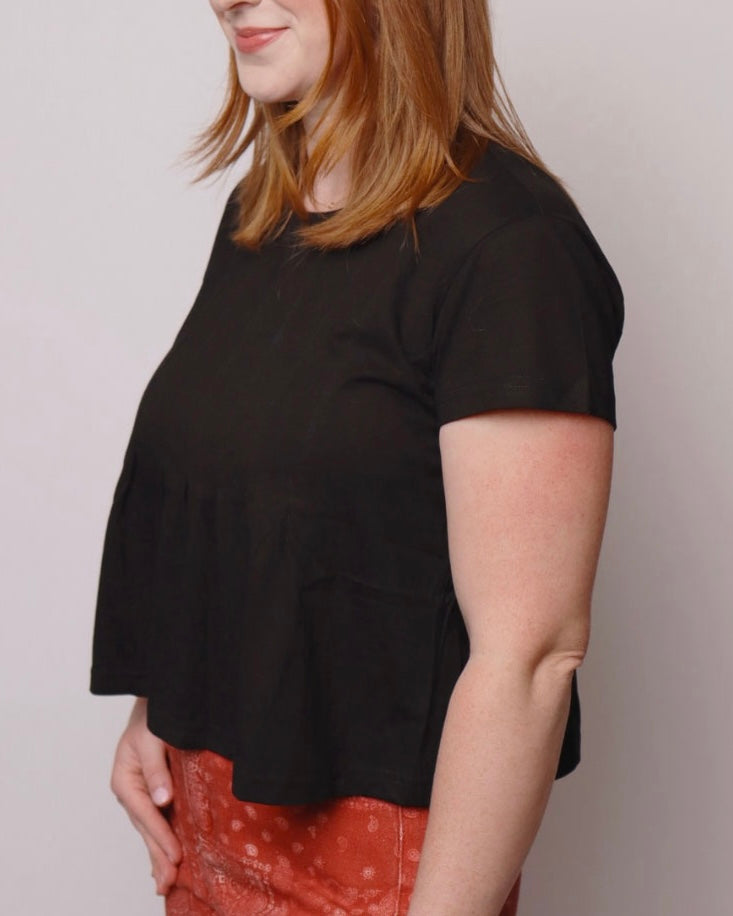 Person wearing a black t-shirt with a plain background
