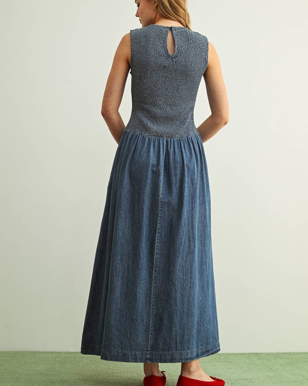 Woman wearing a long denim dress with a plain background