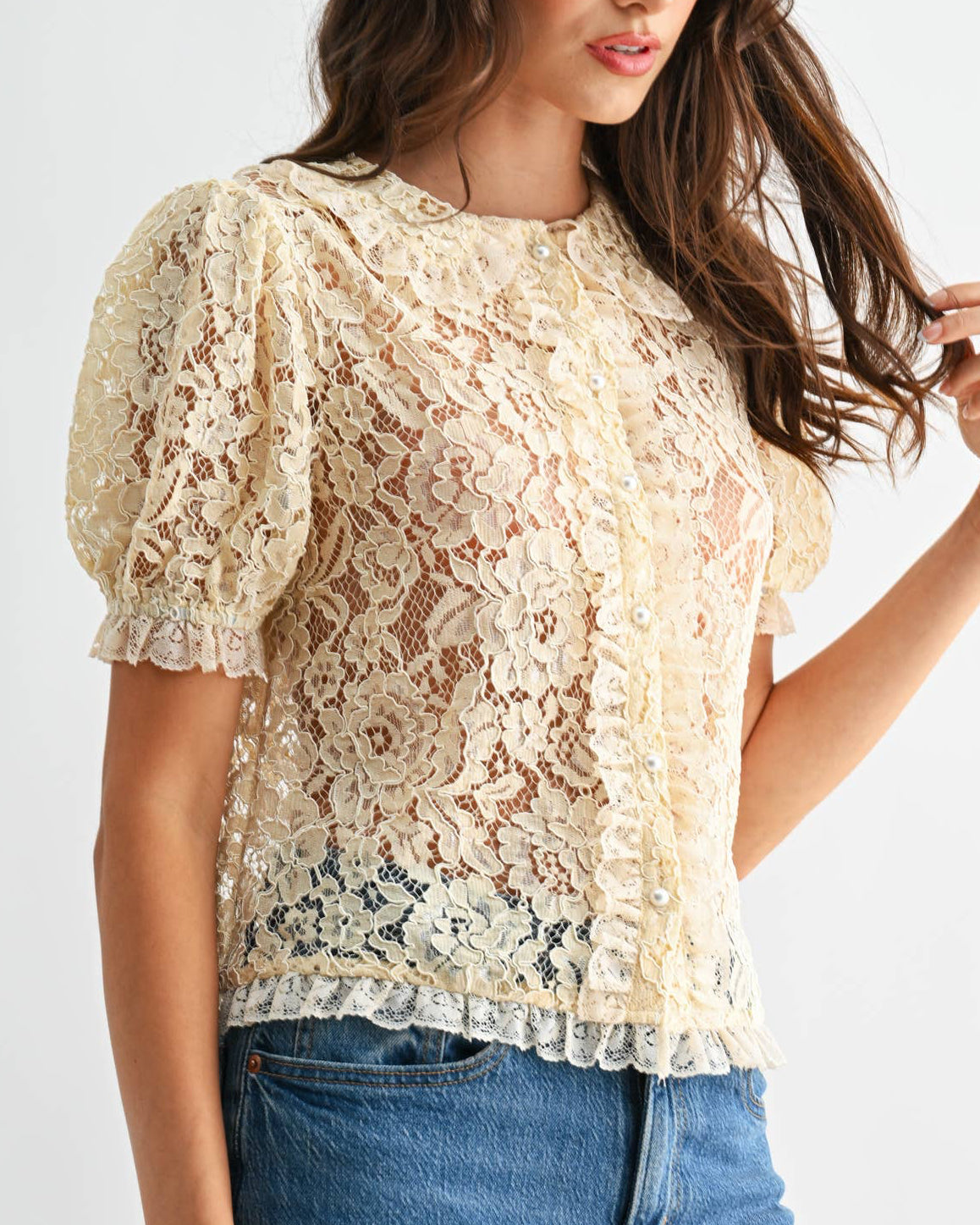 Woman wearing a lace top and blue jeans on a white background